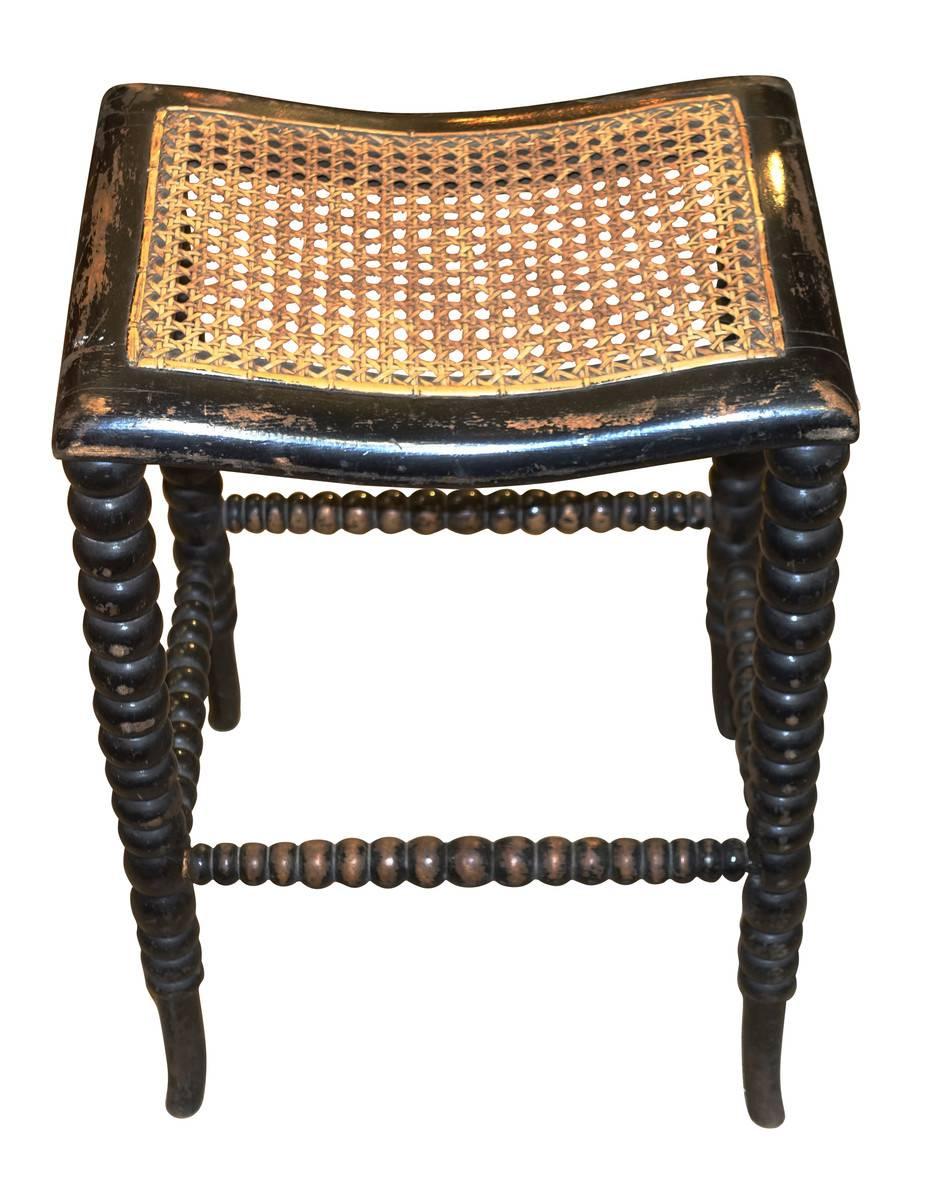 19th century English charming ebonized spool leg stool.
Naturally aged patina.
Unusual slightly curved seat with original cane.
   
