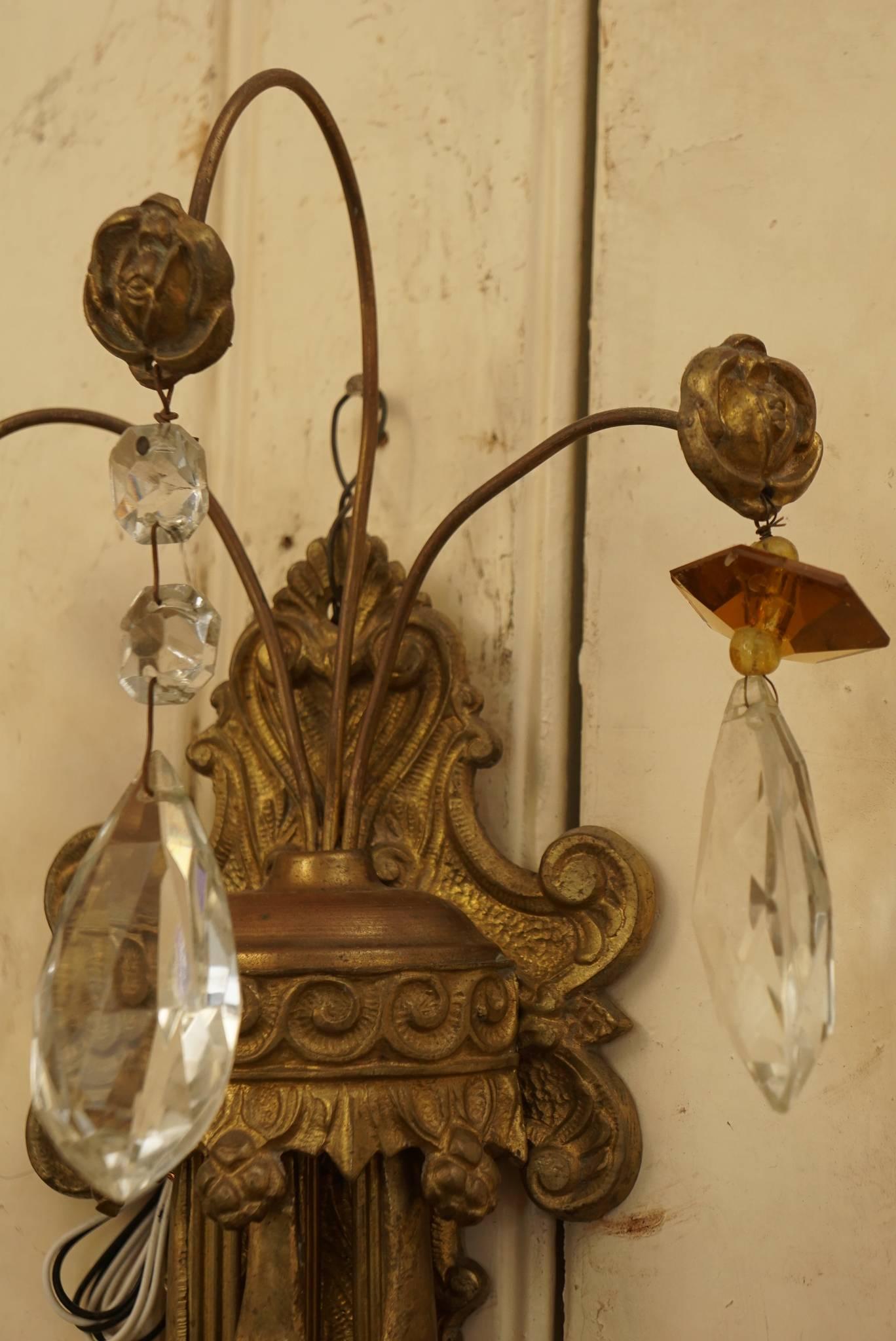 This lovely pair of sconces made in France during the 1920's are cast in bronze and have three lights. The castings include flower heads, foliate vines and leaf work as well as elongated gouache decorative elements. Accented with many hand cut clear