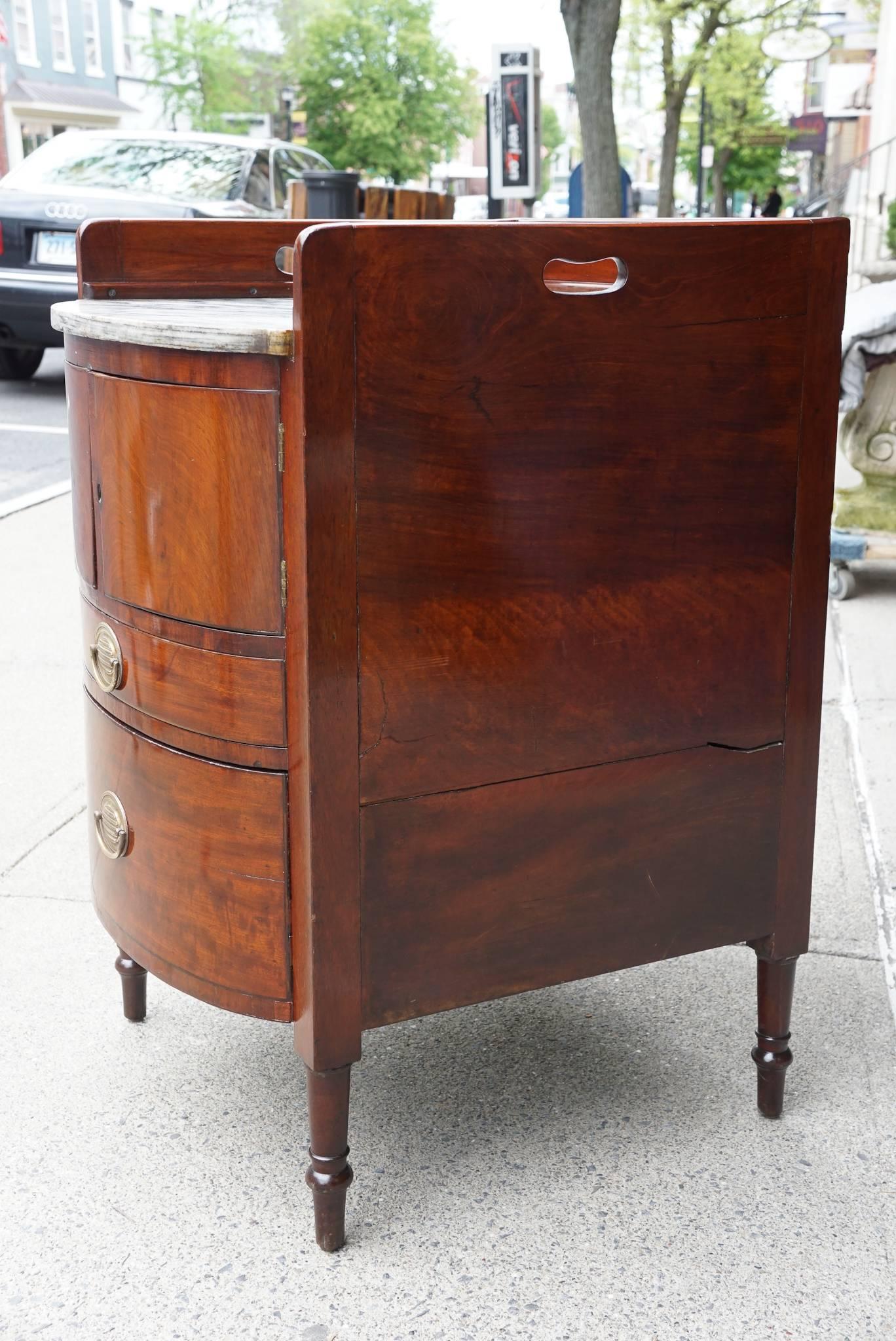 This marble-topped bedside cabinet was made in England between the final years of George III reign and the Regency period. Crafted circa 1800 from imported mahogany the cabinet is deep and very useful still as a bedside table but was once used as a