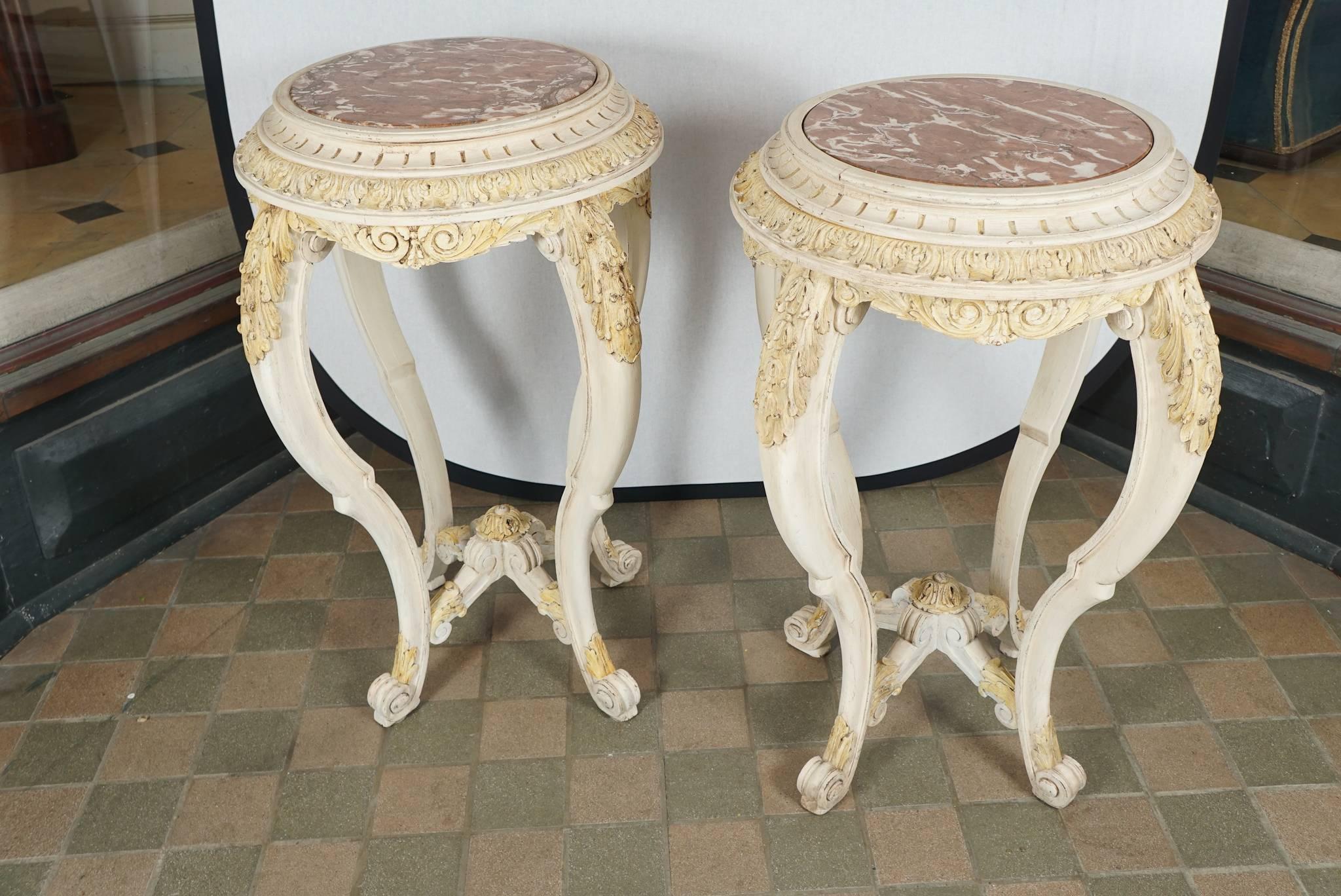 The pair of tables was made in France between 1890 and 1900. Designed in the Louis XV style the pair has extensive hand-carved decorative elements including acanthus leaves, fluting and rosettes all picked out from the cream ground in a light ocher