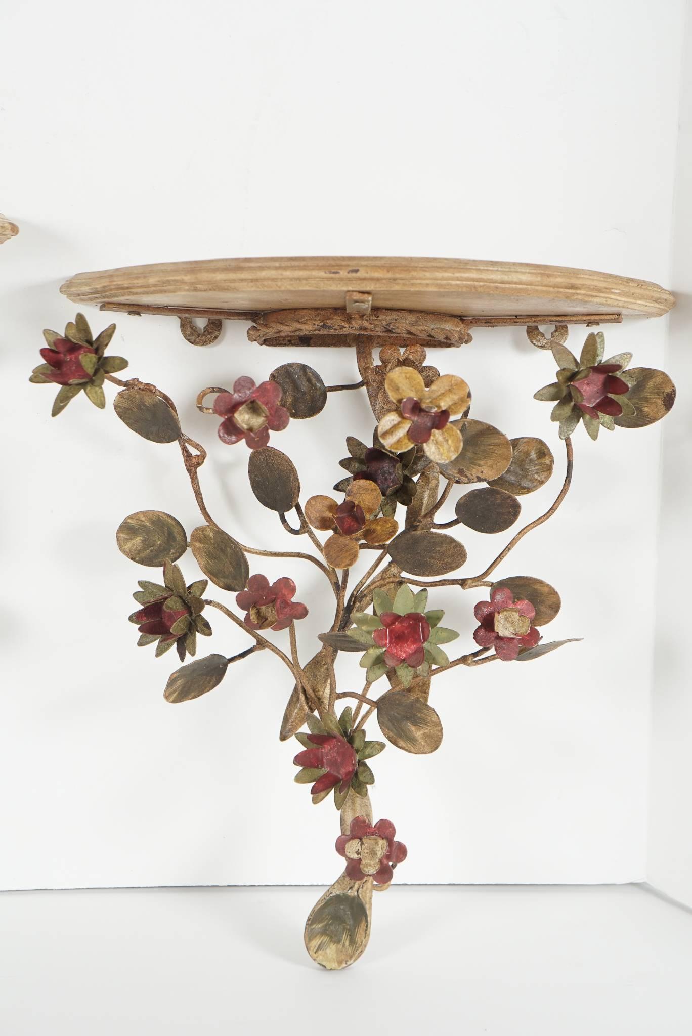 This lovely pair of tole peinte wall brackets from the estate of Mrs. Bunny Mellon are most likely French but might be Italian specifically Piedmontese. Crafted by hand in the form of flower heads and foliage forming the support for the shelf. All