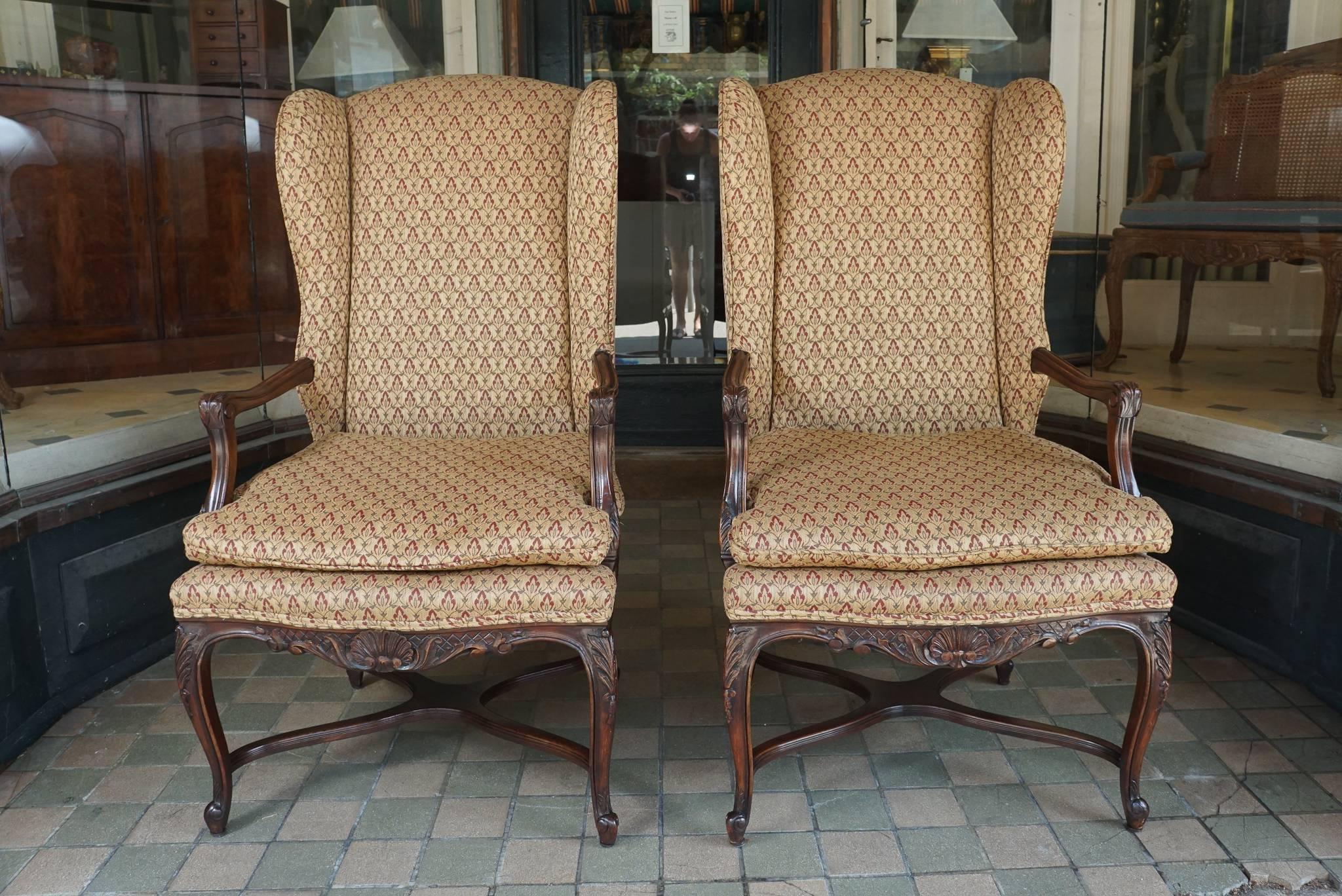 This nice pair of wing chairs are comfortable and solid. Crafted in the late 1950s most likely in France the pair is made from walnut and are well carved compared to most furniture produced in antique styles from the period. Made in the Louis XV