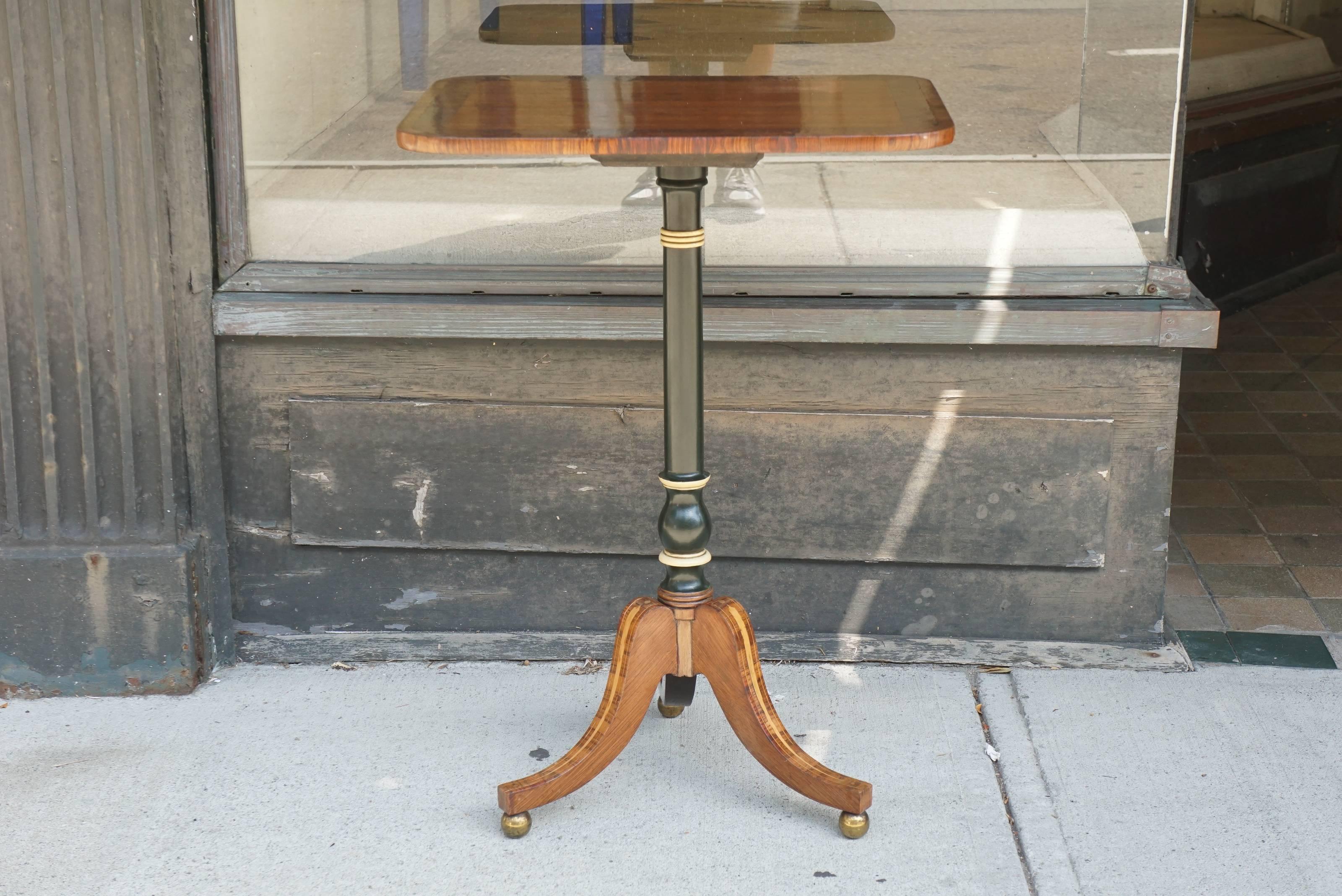 This fine small table is beautifully crafted. The top is blond mahogany banded in burled walnut and trimmed with rosewood. The ebonized and polychromed stem support rests on three splayed legs with large holy inlaid spears running down the center of
