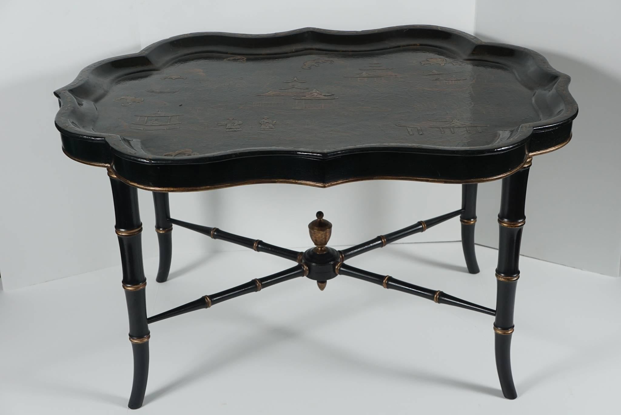 This lovely 19th century papier mâché lacquered tray set upon a later stand decorated to match comes from England. The tray was made circa 1850 and shows a nicely done oriental overview filled with people, buildings, bridges and trees all set in a