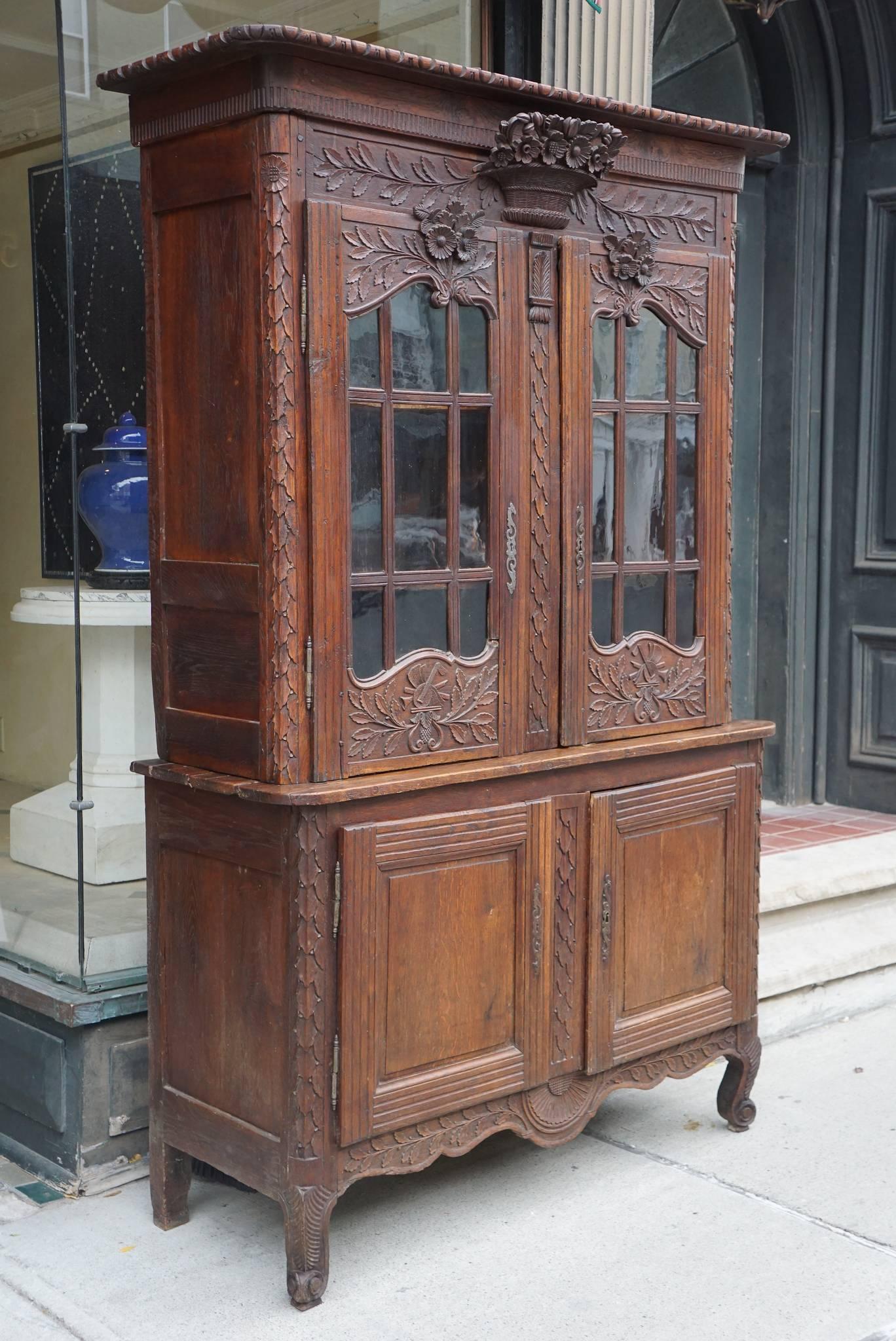 This nice and compact-sized buffet with glazed doors comes from the Normandy region in France and was made, circa 1770 during the reign of Louis XV. Created using dark stained oak a difficult wood to carve the piece is centered on its carved and