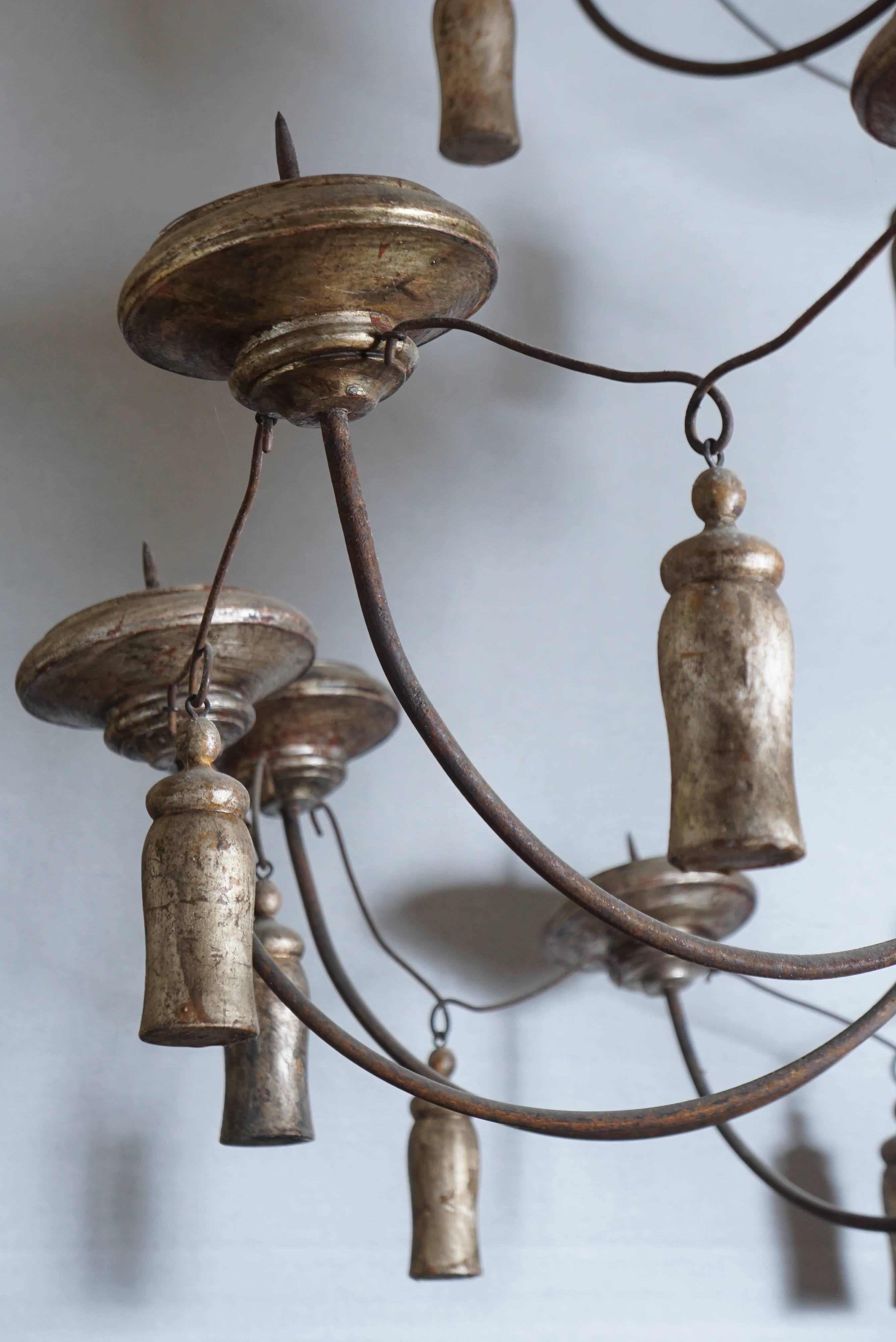 This very large and monumentally scaled pricket light fixture was made in France in the 18th century and over the years it has had some newer parts made and added but is essentially as it was made. The shaft and candle bobeche are carved wood and