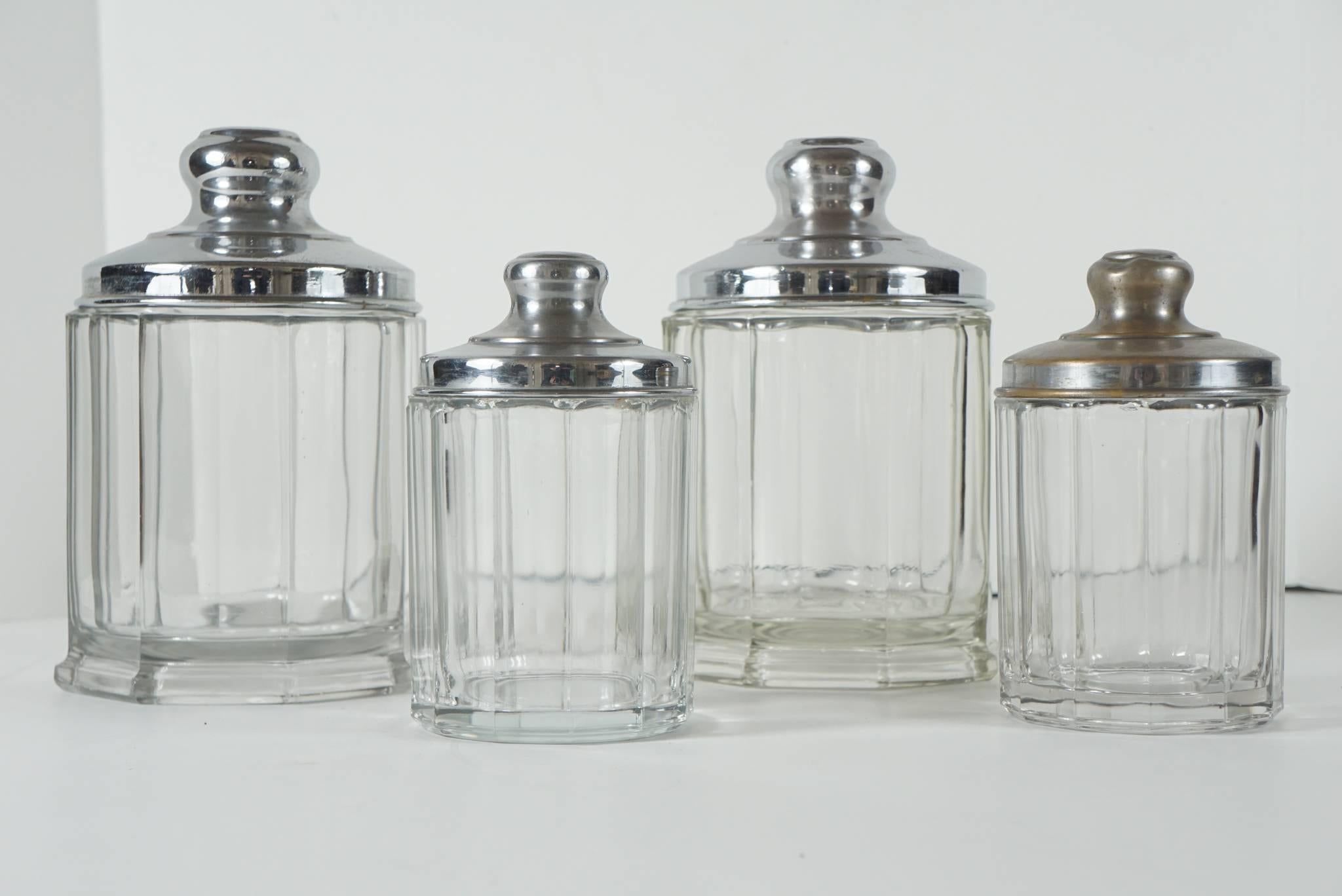 These jars were made in the 1920s and were designed as covered containers that register the contents at a glance The glass is thick and nicely segmented with chrome plated brass lids . Created in two different sizes the lot contains four jars two of