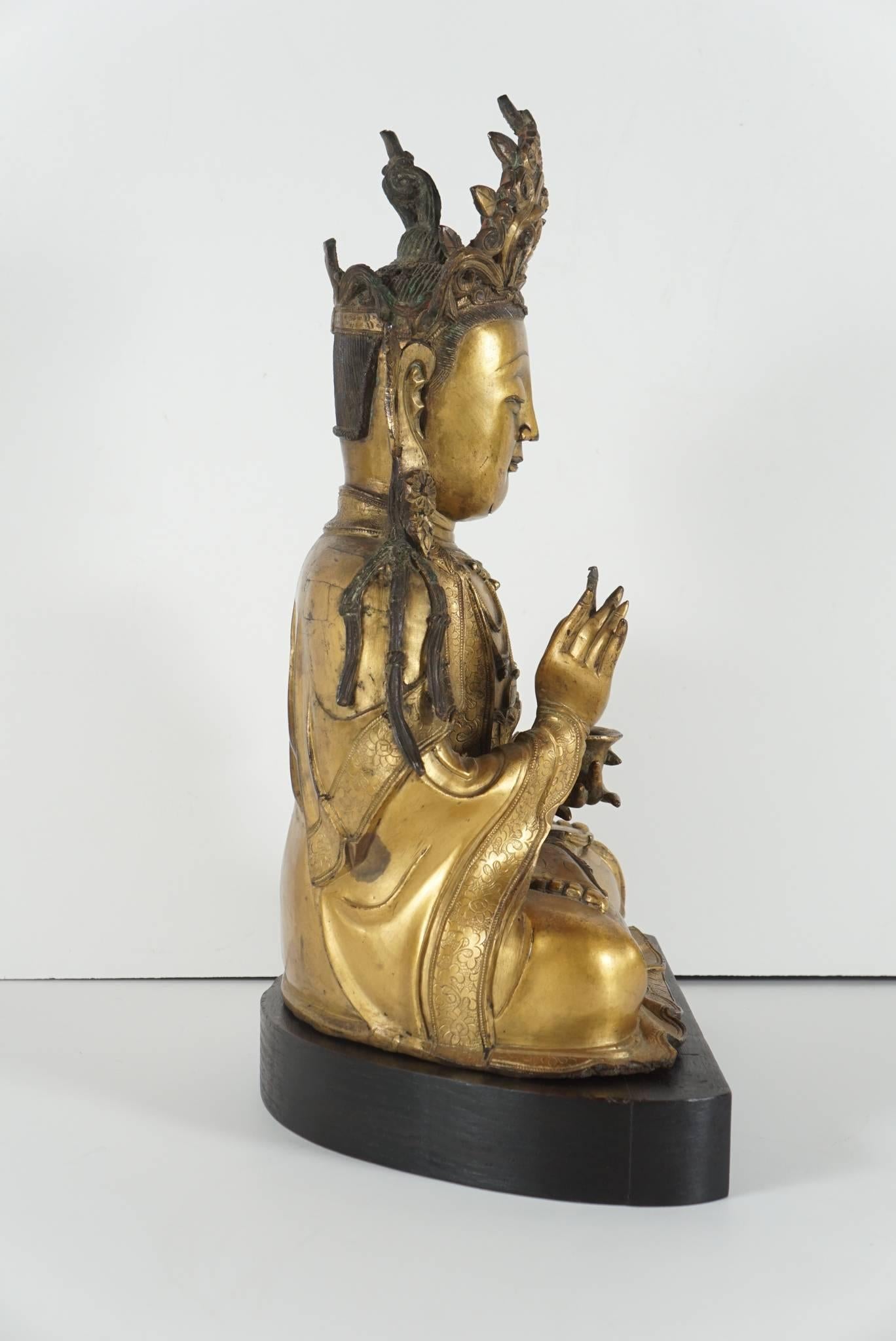 This very finely cast figure seated in Vajrasana posture shows many detailed refinements such as the jewelry, crown, lovely almond shaped downcast eyes, engraved rob patterns and the well shaped folds of drapery. The figure as well wears a patch