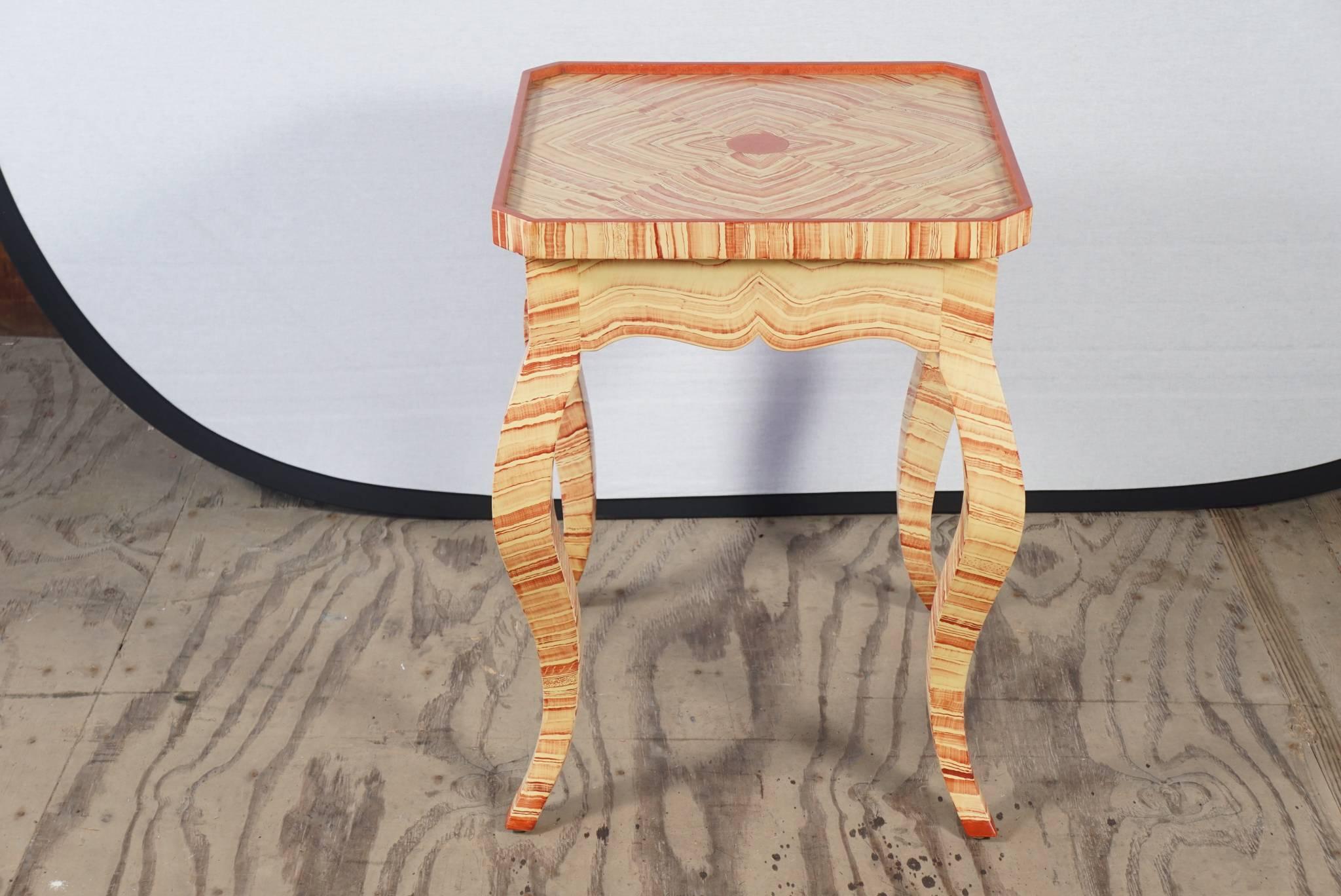 This table made in an Italian style with a tray top and canted corners with cabriole legs is painted in an agate patten that is bookmatched thru out. The colors are deep and rich on a creamy ground and the painter has signed and dated his work which