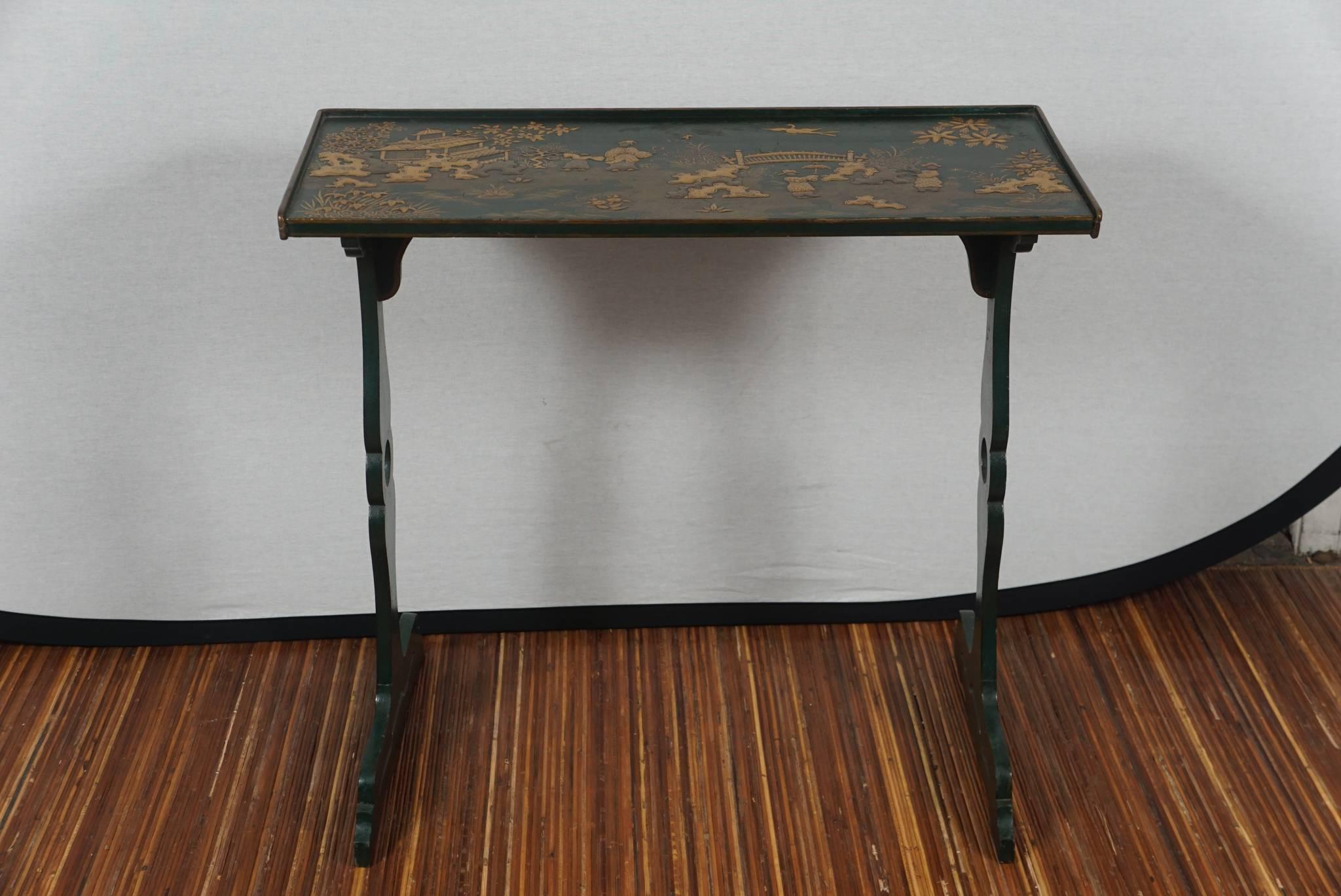 This lovely fine old table was made in England, circa 1900 during the Edwardian era. Decorated with japanned scenes of court ladies and gentlemen in a luscious oriental landscape with buildings and trees the color ground is a deep green blue with