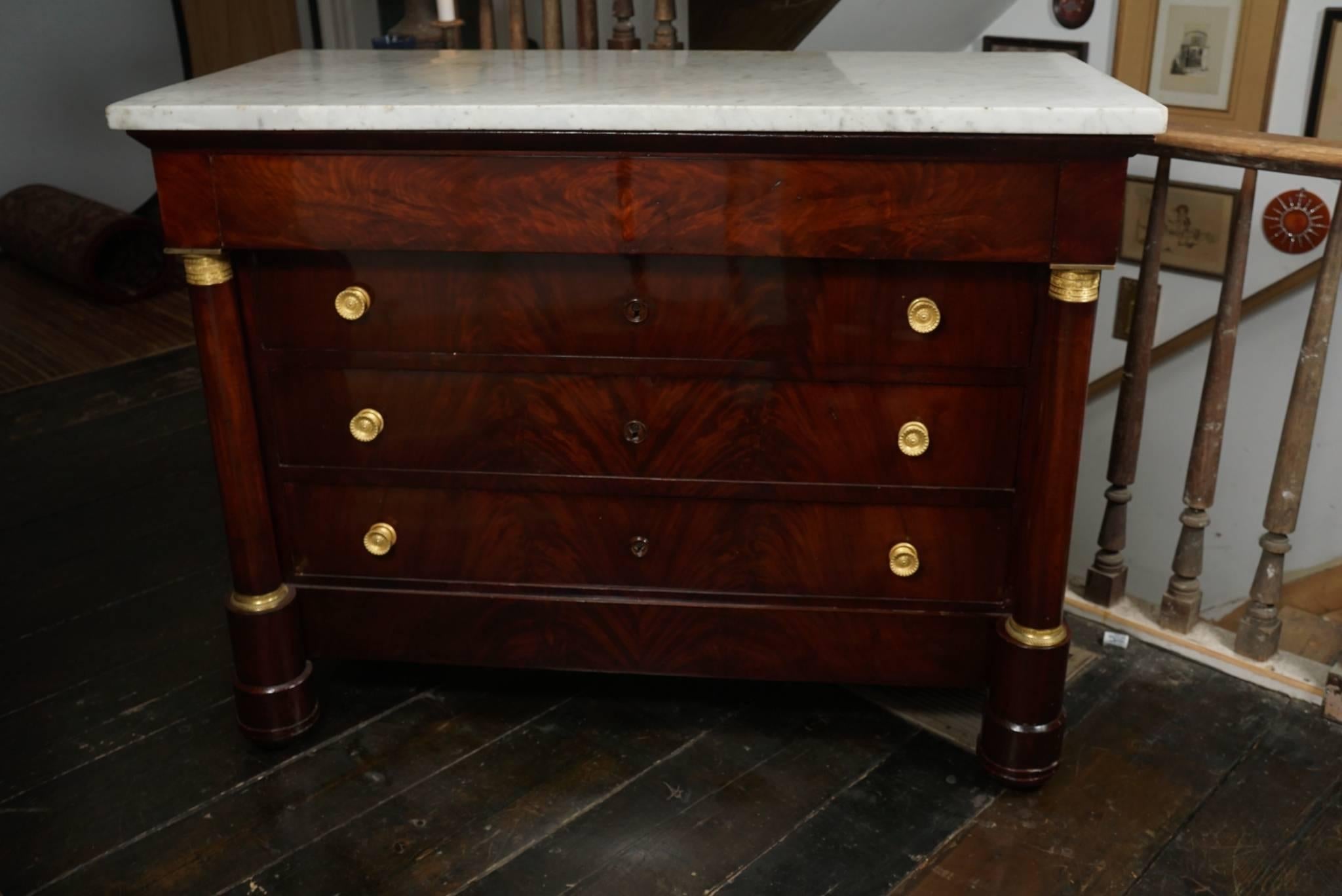 This commode, circa 1810 was made in France of costly imported mahogany. The veneer selections contain the crotch flamed pattern running up the front across all four of the drawers. Each drawer has finely chased pulls with the drawers centered