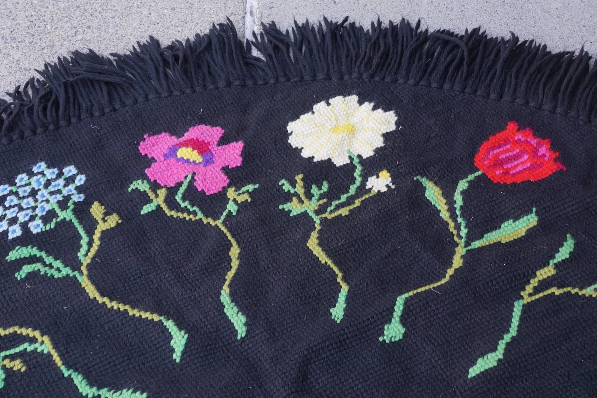 This rug somewhat unusual for its strong black background and the vibrant color selection comes from the collection of Bunny Mellon. Well known for her discerning taste and a life time of philanthropy Mrs. Mellon's driving passion was flowers,