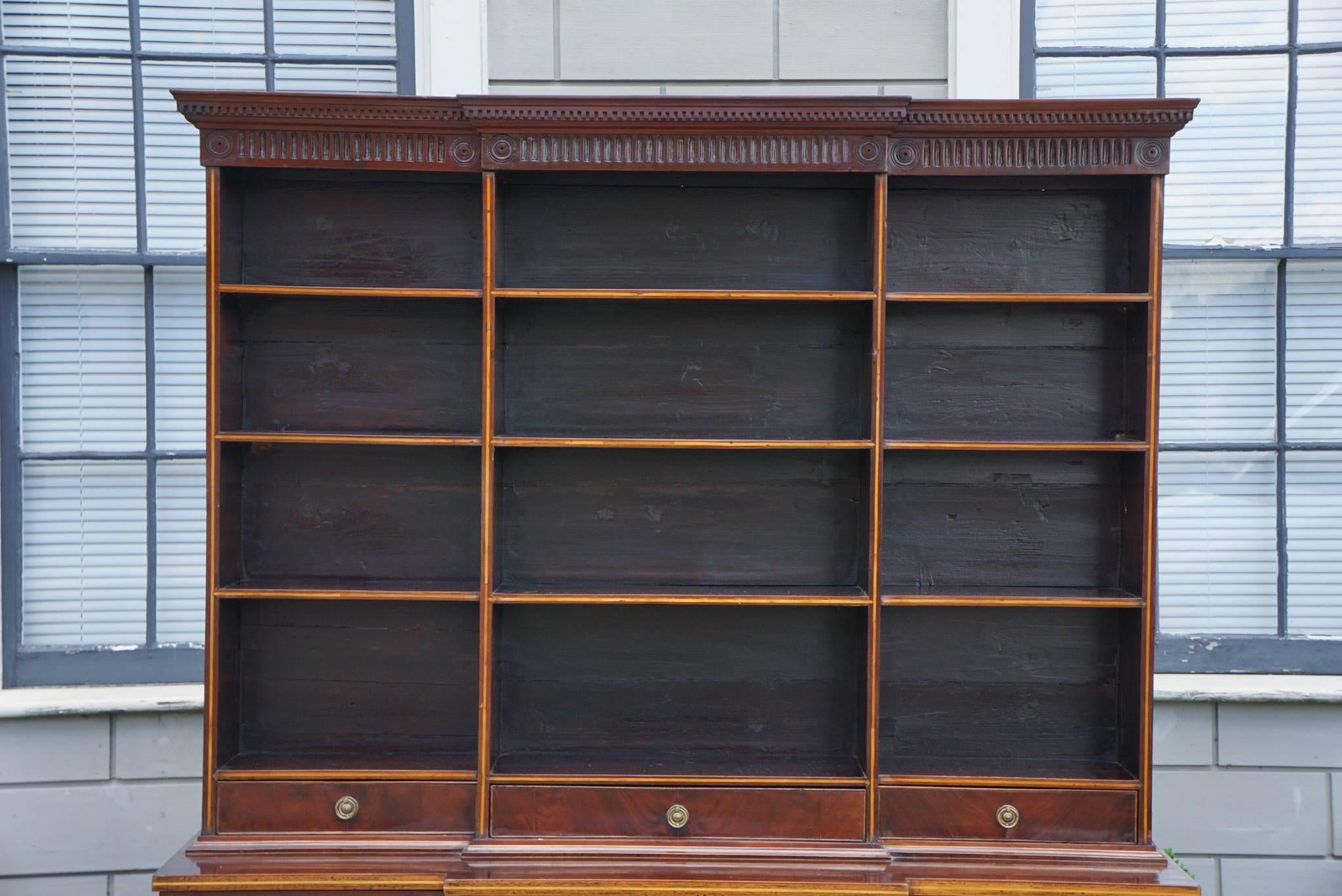 This nice open bookcase of easy to use small size was made in England at the end of the reign of George III circa 1800 to 1805. Just before the Regency period which this shows some affinity with by its use of a decidedly contrasting satin wood
