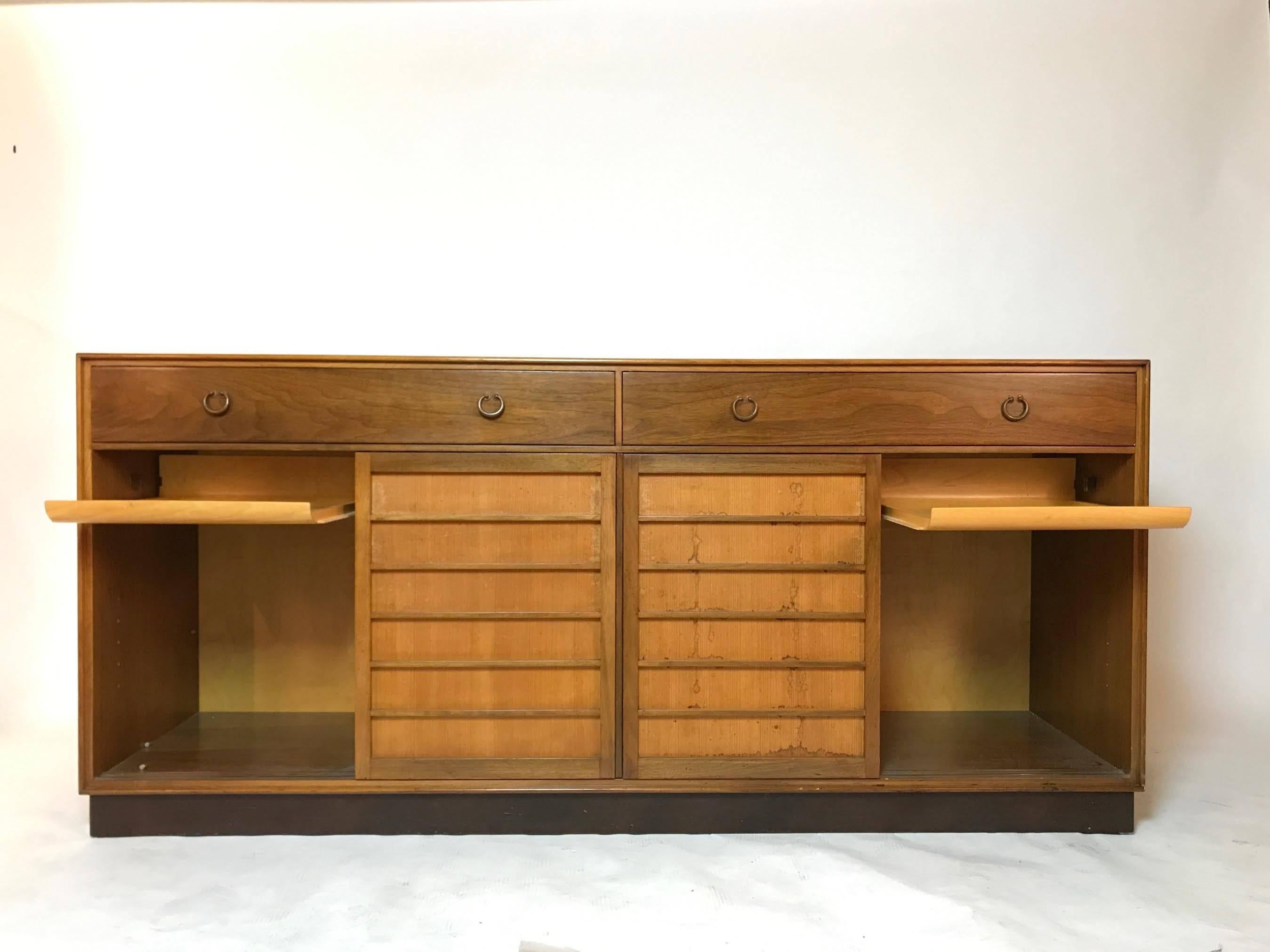 This sideboard designed by Edward Wormley for Dunbar is an Early Example from the 1950s
(Model 671A Berne Indiana)
Walnut
Rectangular top over four sliding doors. Interior fitted with pullout trays. Green Dunbar label.