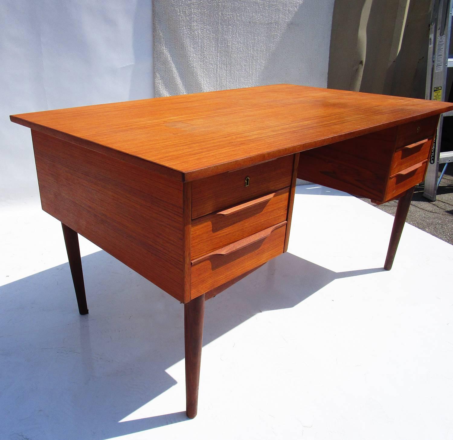 Classic Danish design with a unique bookcase front. The desk is in solid condition with original finish, showing spotting on top surface.