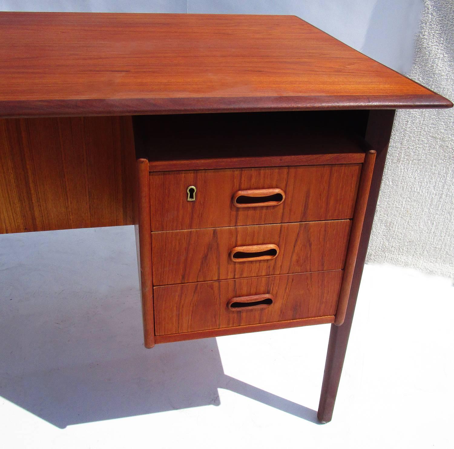 This great desk has all the hallmarks of Classic midcentury Danish design, clean, uncluttered lines and natural woods. The desk is a stained teak wood, and shows well. There are minor signs of wear and a couple water spots on the top surface.
