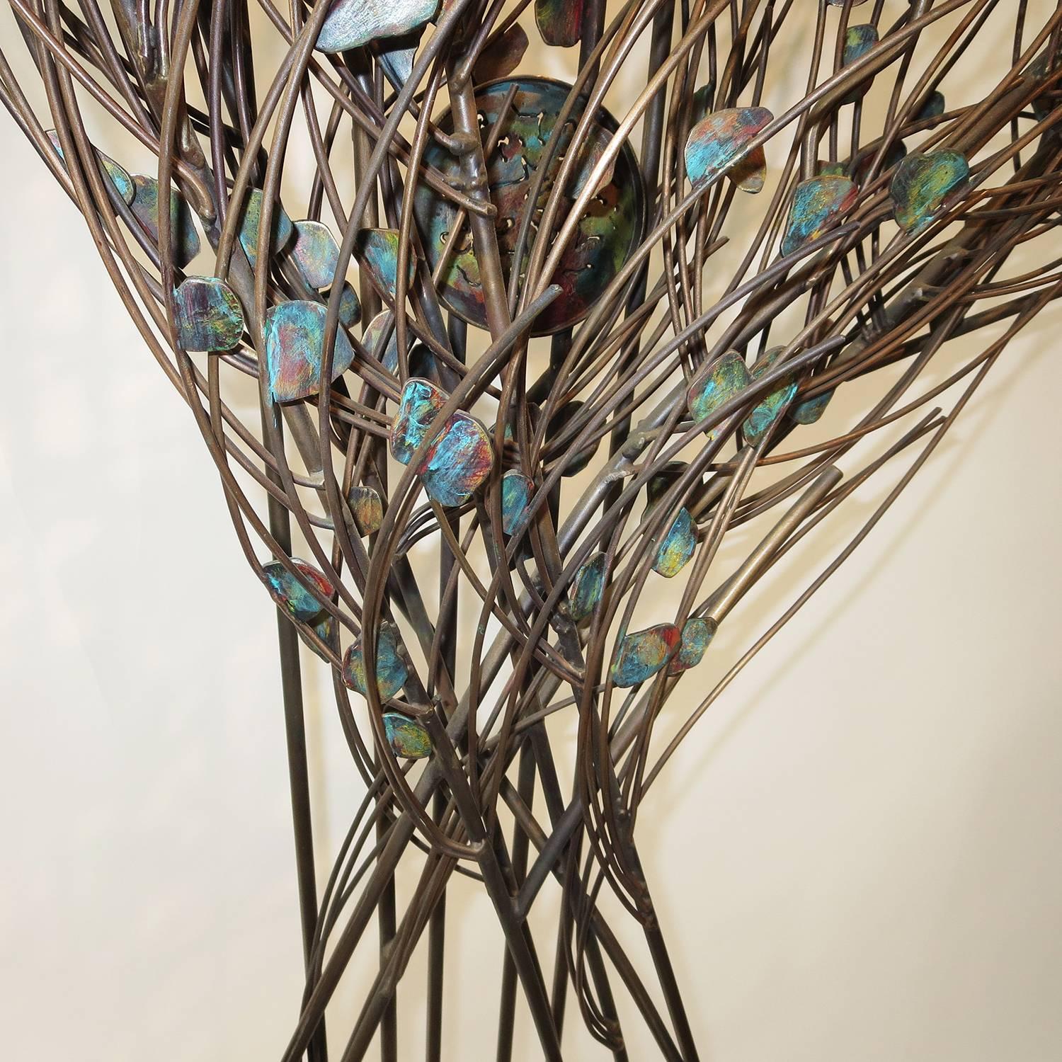 A powerful work by Pacific Northwest artist Penny Mulligan. A simple and orderly form gives way to a motion of storm in the upper half. The leaves and discs are multicolored, and the discs are pierced in random patterns. The work is boldly signed in