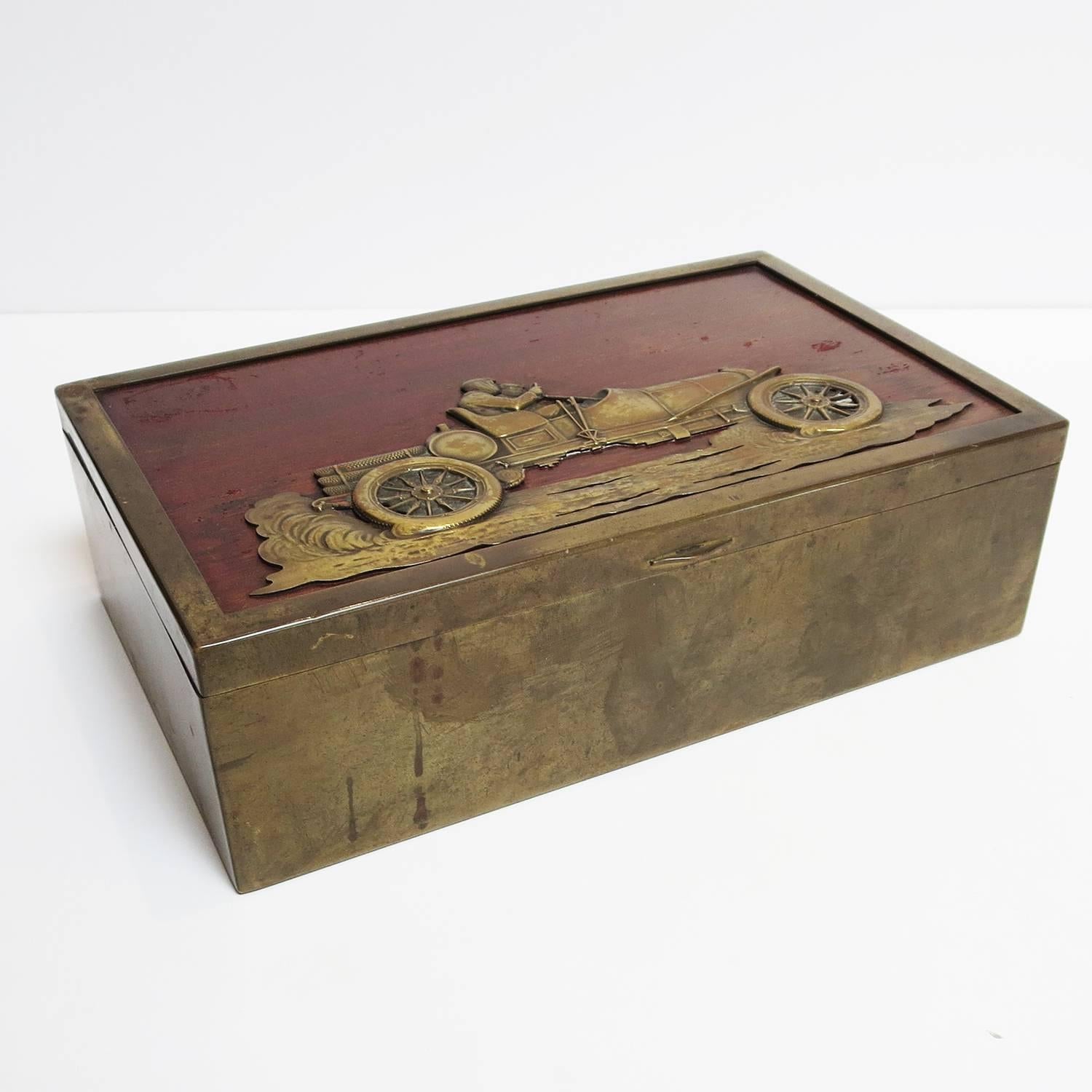 This fantastic box is the ultimate desk top box for any automotive enthusiast. The box, and the car represented on top, and from the late teens, early 1920's. The car is kicking up the dirt as it speeds along, and is a raised hammered bronze or