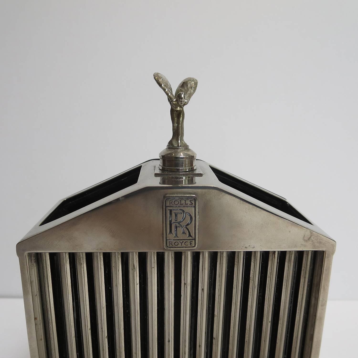 Write with taste! This lovely pen holder is fashioned after a Rolls Royce front grille, complete with emblem and winged woman radiator cap. Finished in a dark nickel, it displays only minor surface imperfections of age. The back is finished in a