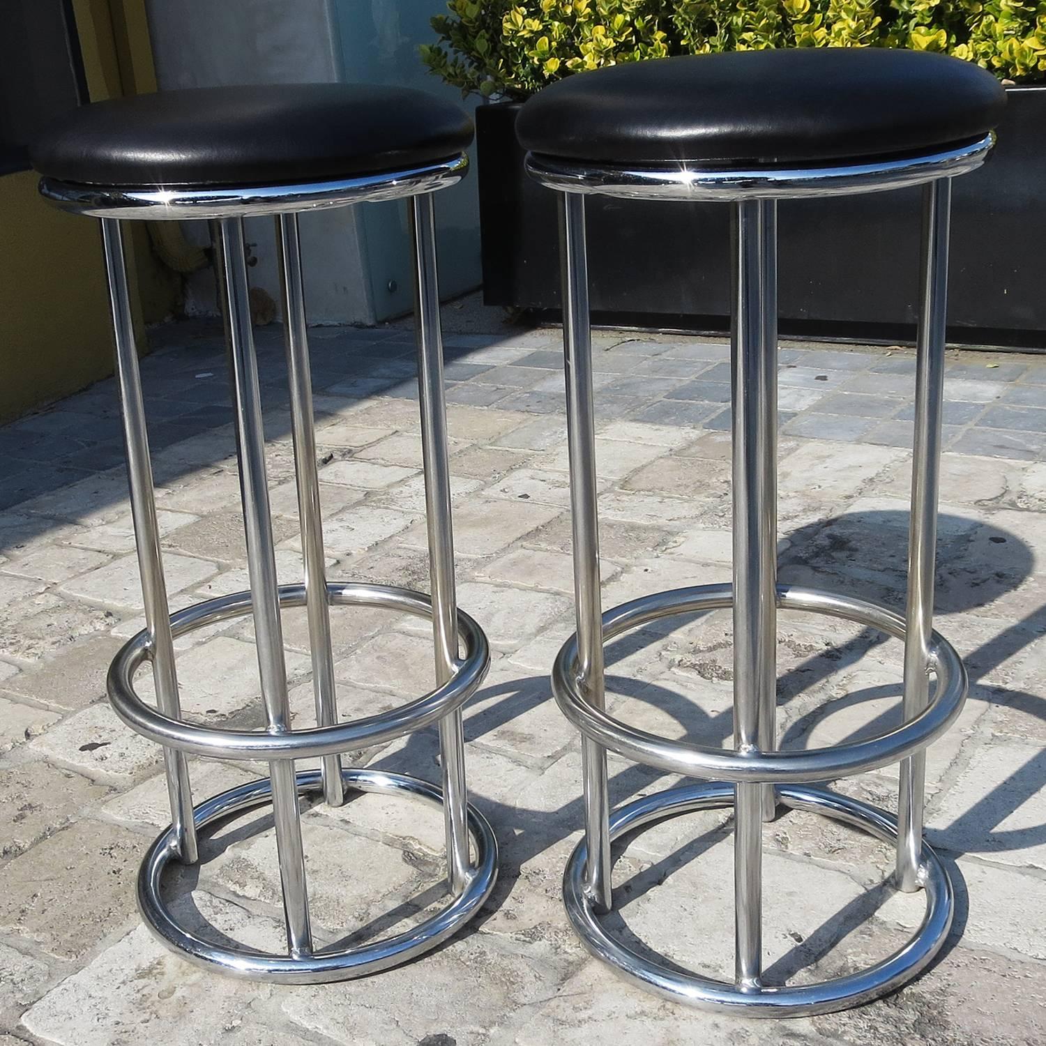This charming pair are unique in their form. Most stools in tubular chrome end in four legs to the floor, while ours have a stylish ring to finish them off. The chrome is in fine original condition, showing only minor wear. The seats have been