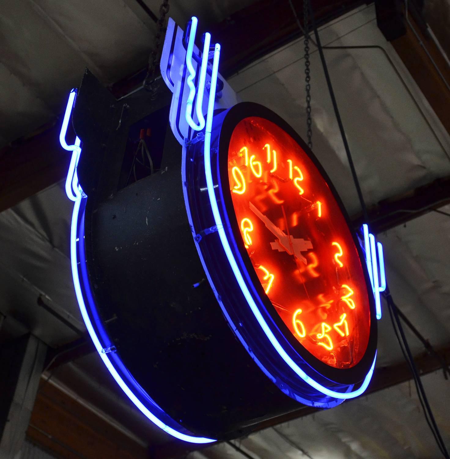 A very rare and wonderful neon clock, with a lighted face on both sides. These were hung outside a storefront, to be seen from a distance in both directions of traffic. The faces are porcelain enamel, including the clock faces. Two colors of neon