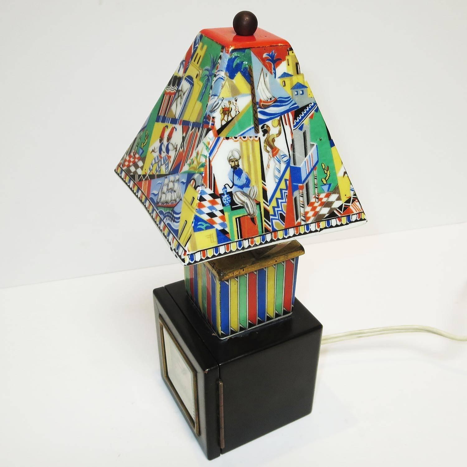 This wonderful small lamp is perfect as a bedside night light and clock, or anywhere a splash of color is needed. One is drawn to the shade, which is hand painted china, in a Moroccan theme. The color scheme is carried on in the ceramic column of