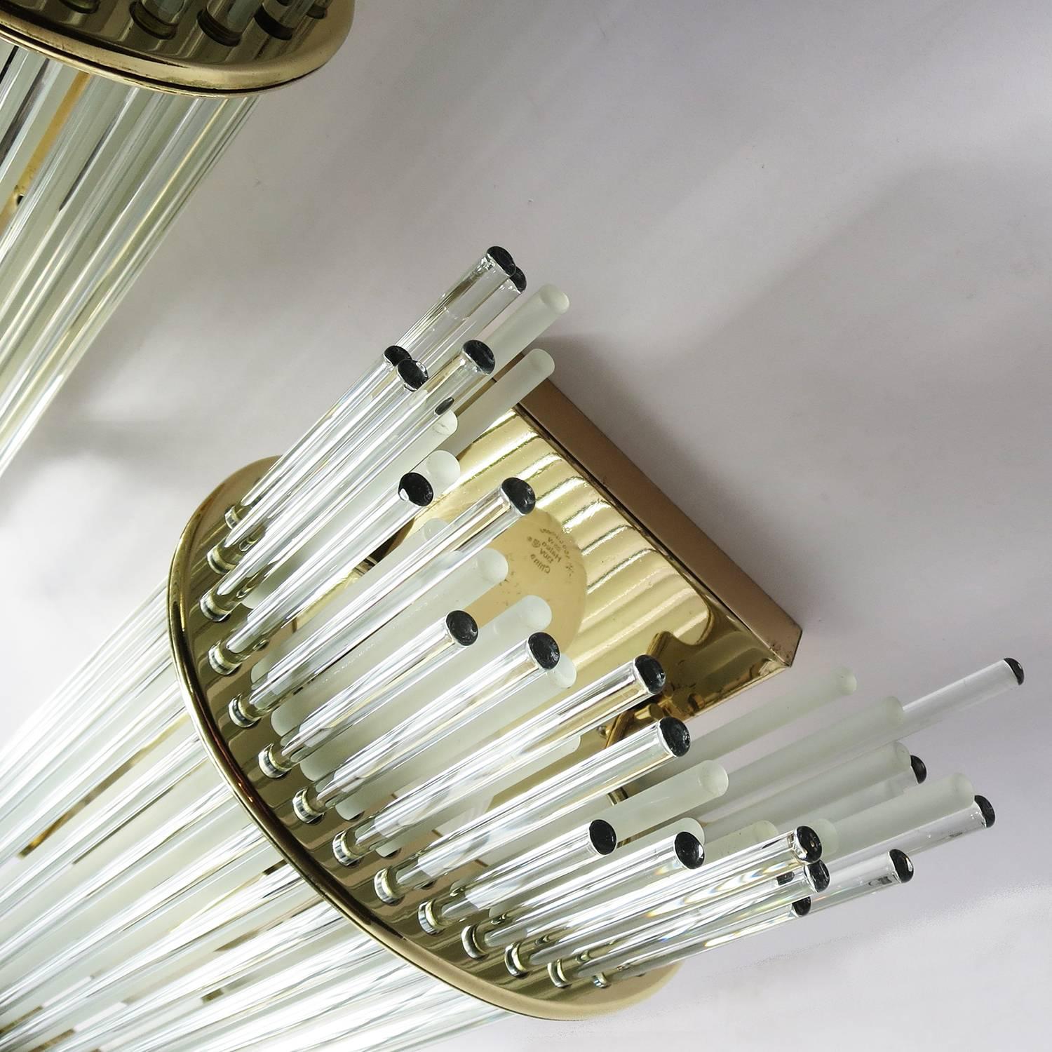 A very unique design utilizing thin glass rods as shades. An inner row of frosted rods helps obscure the bulbs, while the outer row of glossy rods add the sparkle. The fixtures have been re-plated in brass, and display very well. There are two