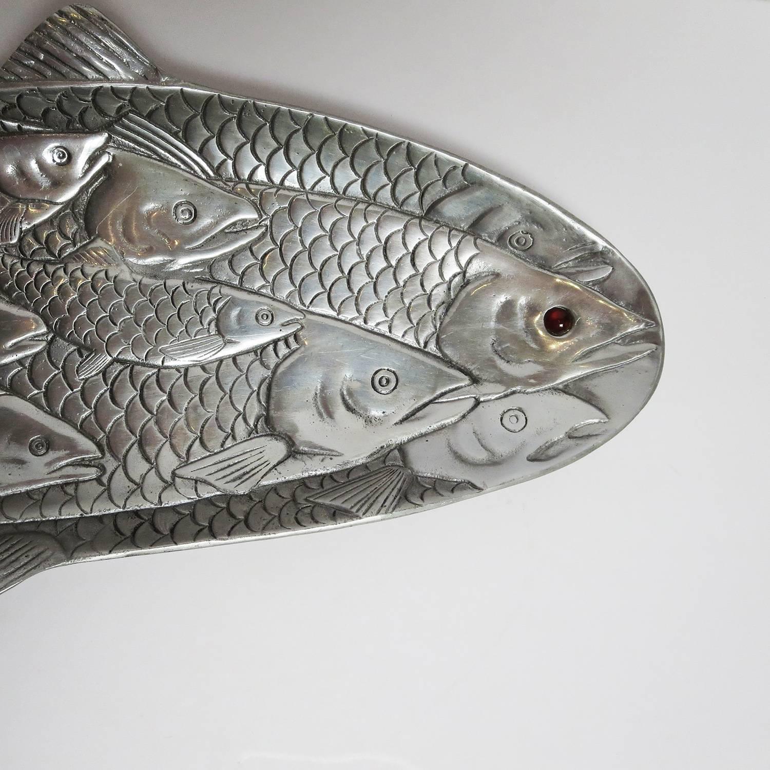 This highly stylized fish platter comes from America's master of aluminium, Arthur Court of San Francisco. The platter is chased decorated on both sides, in a pattern of overlapping fish. The lead fish is decorated with a red jasper eye. The platter