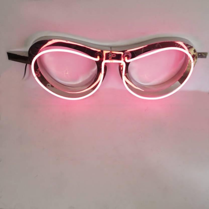 Pretty in pink, this 1950s vintage neon eyeglass sign is iconic and Pop Art all at once. The frame is made of chrome-plated steel and the neon is a gentle rosey pink. A great size and color for household use, the transformer is small and tucked