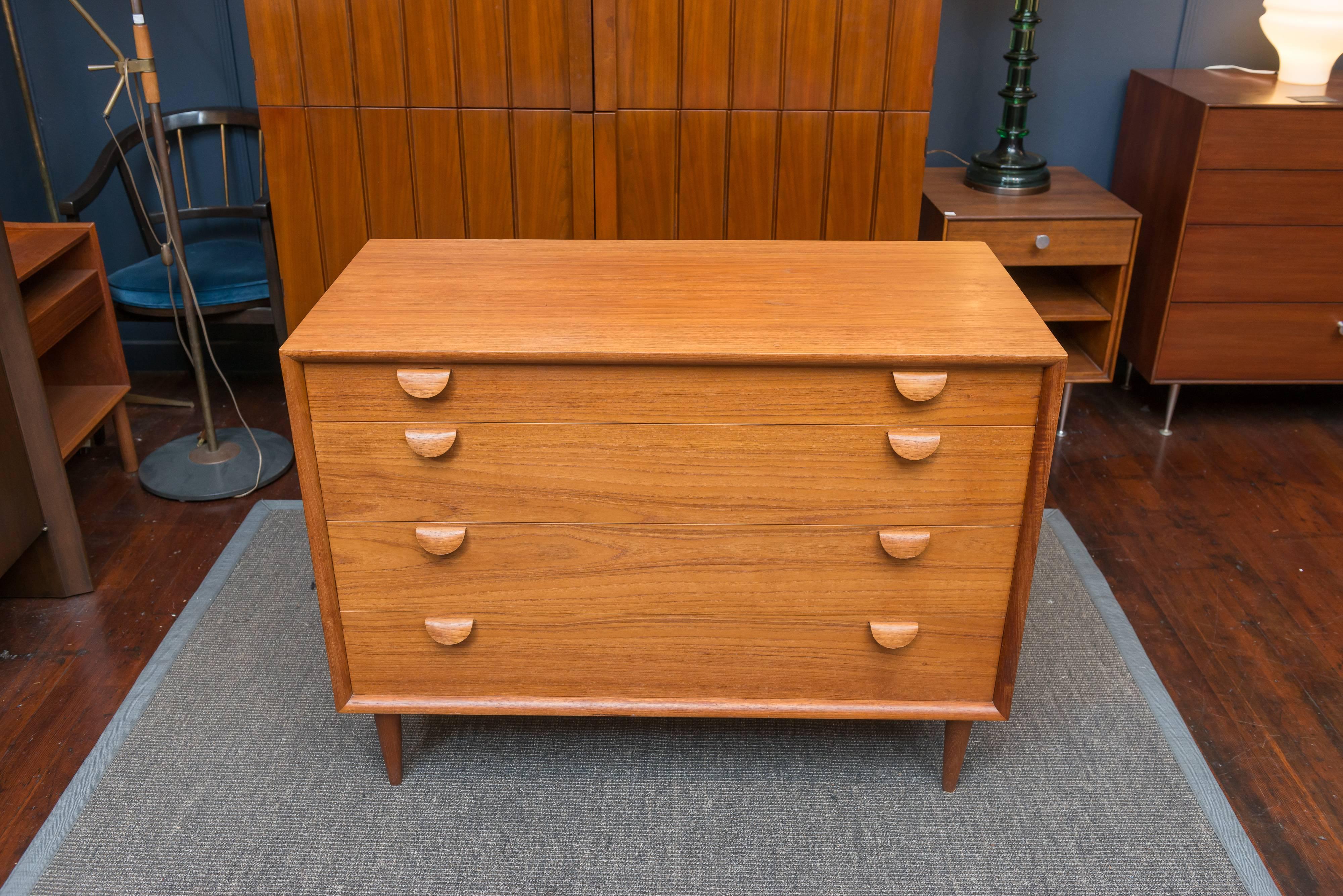 Danish modern design teak chest of drawers with sculptural handles and divided drawer inserts.