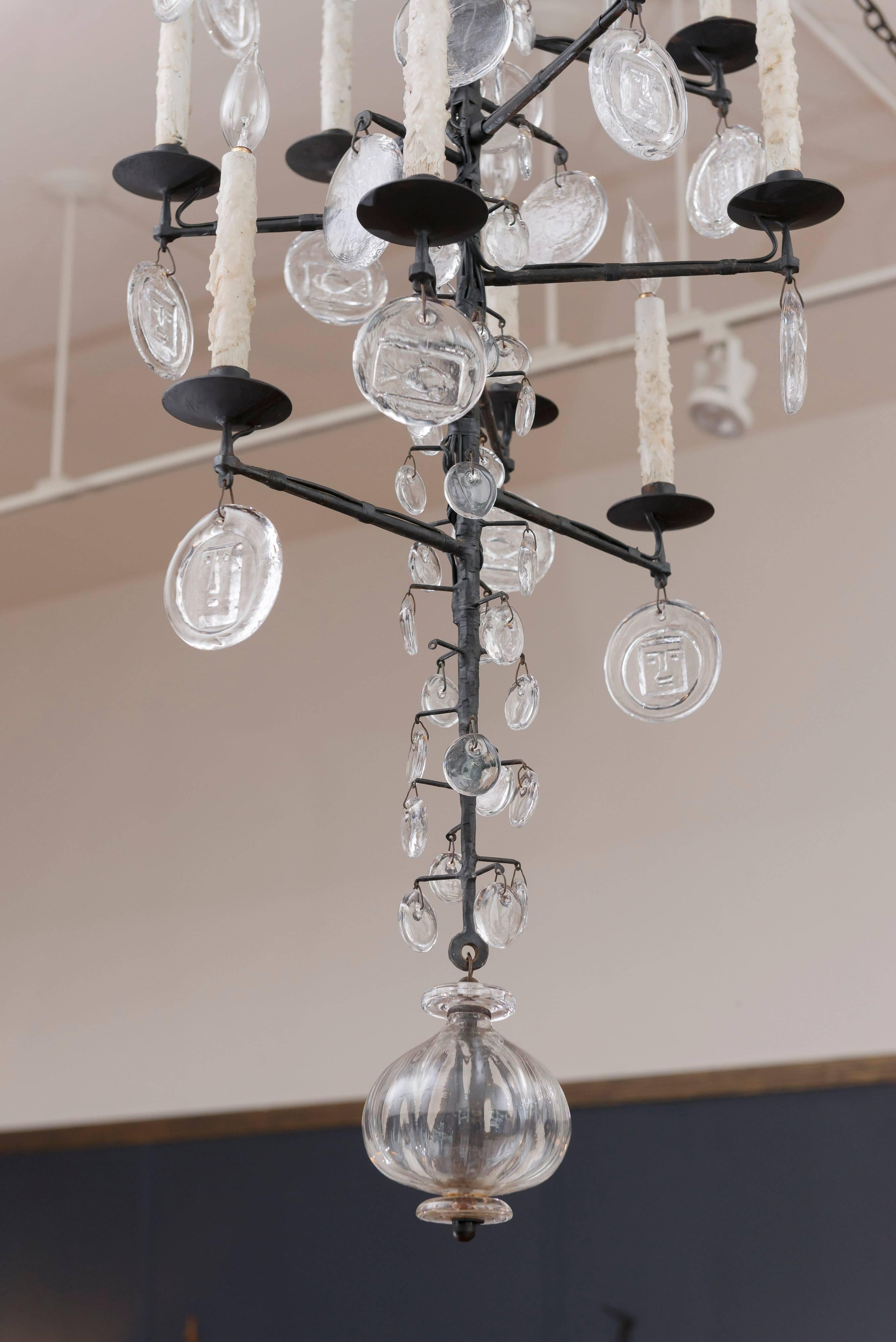 Large and impressive Erik Hoglund design sixteen-light chandelier. Made from hammered steel and decorated with cast glass drops depicting faces, fish and tear drops by Kosta Boda, Sweden.
