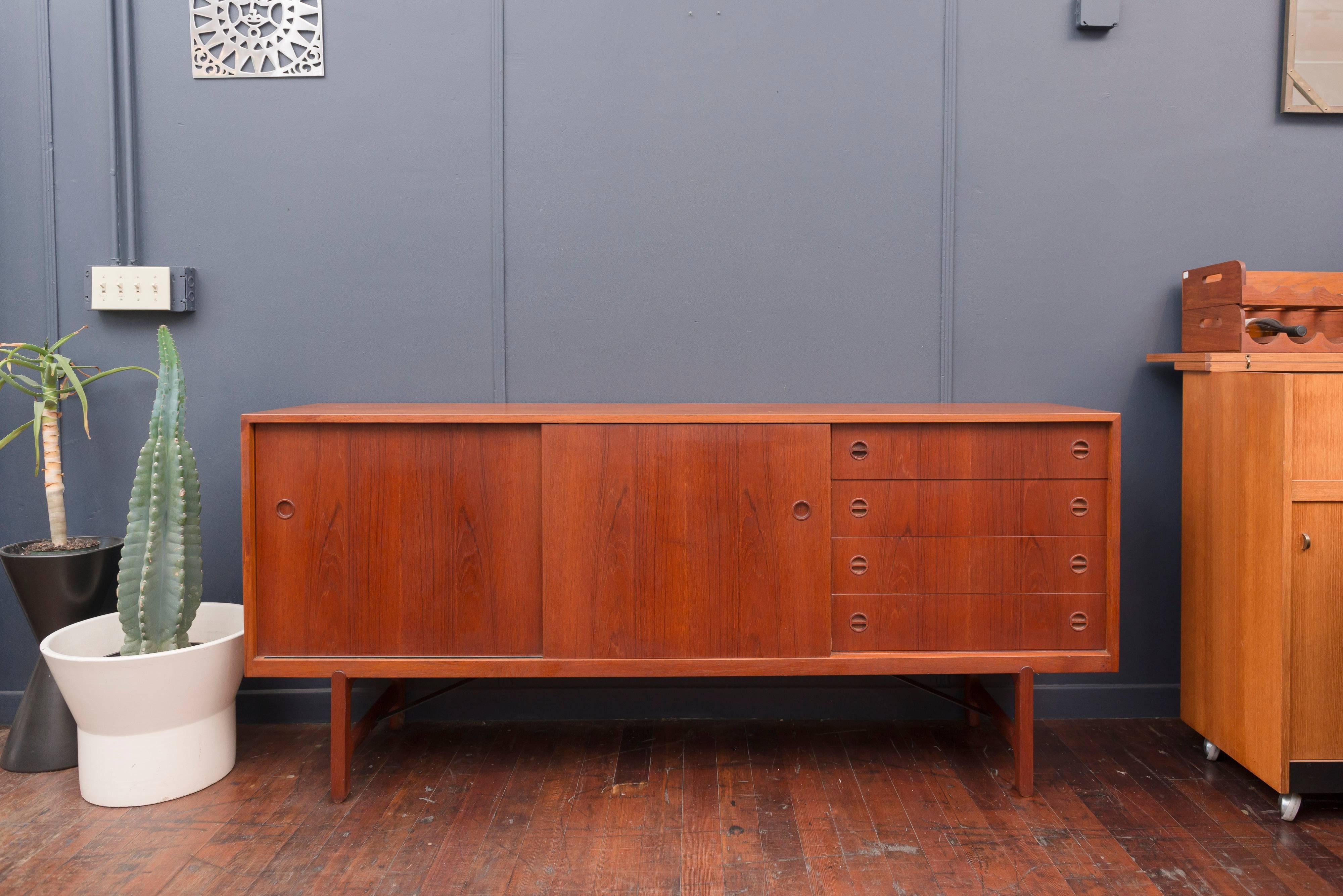 Rare teak credenza designed by Ejnar Larsen & Aksel Bender Madsen for Naestved Mobelfabrik, Denmark. Very high quality construction with two sliding doors, adjustable shelves and drawers. Supported on simple but sculpted teak legs and architectural