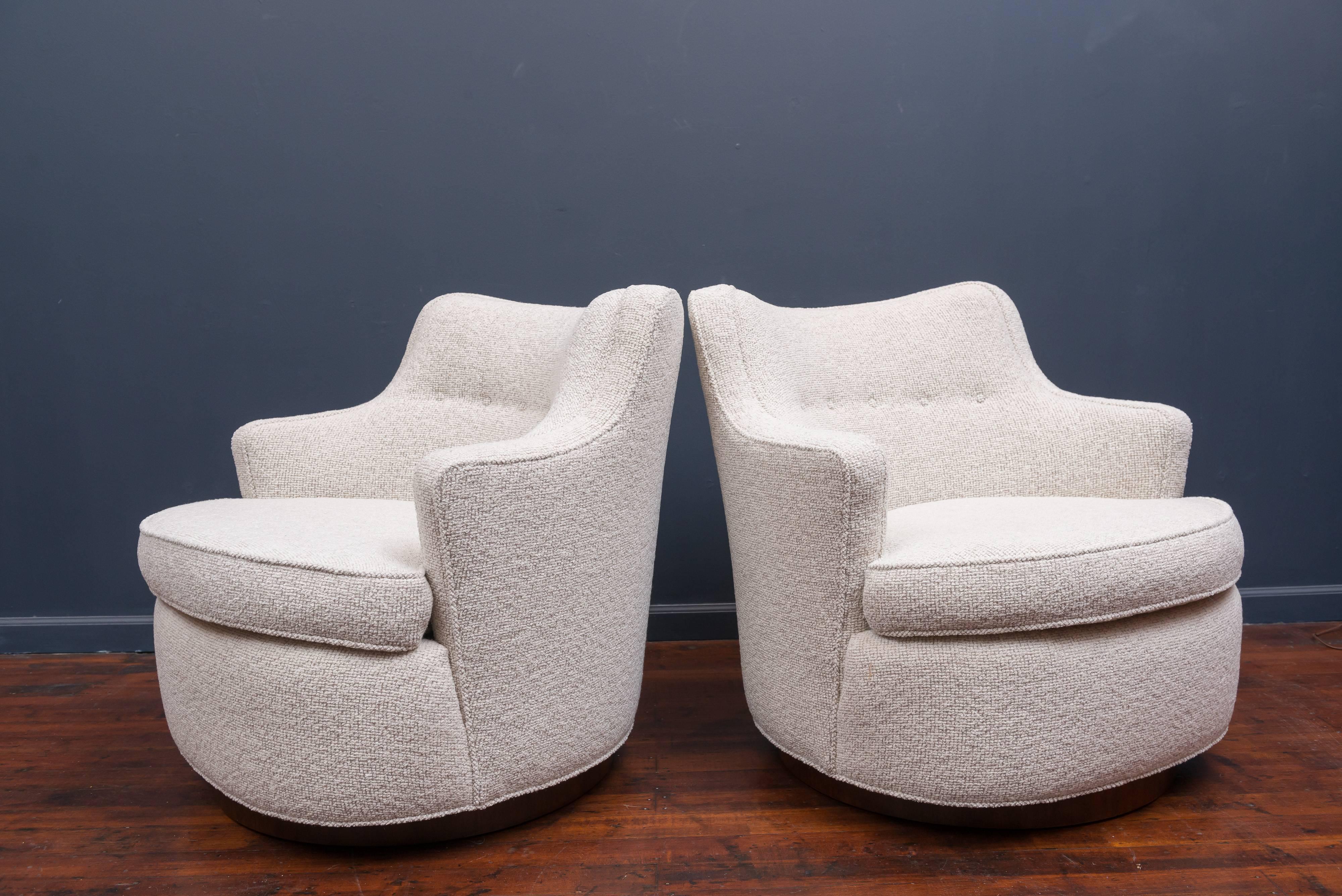 Swiveling lounge chairs on walnut circular plinths designed by Edward Wormley for Dunbar. Perfectly refinished bases with newly upholstered tubs.