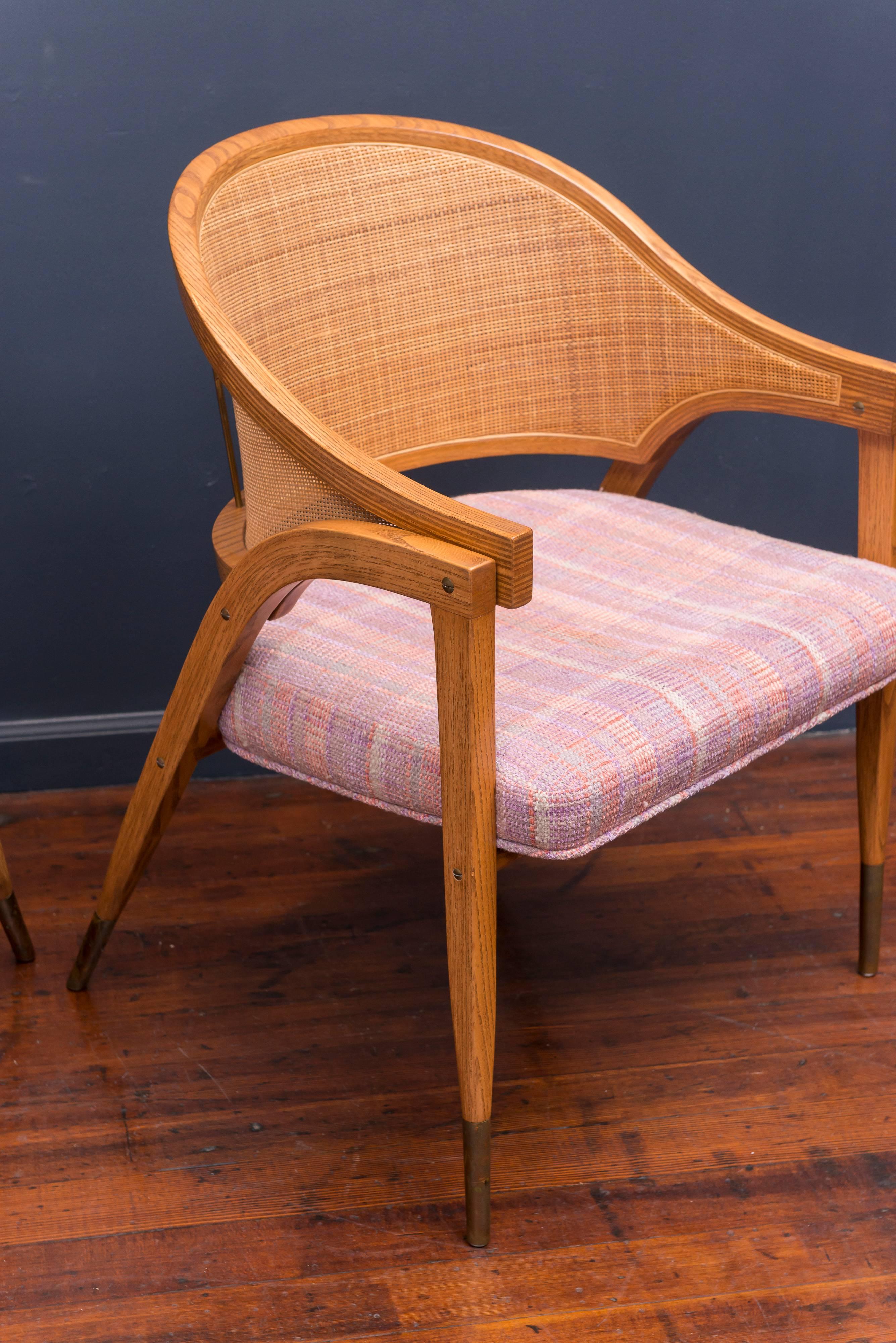 Elegant design armchair by Edward Wormley for Dunbar Furniture co. Berne Indiana Model 5480. Excellent original condition examples made from oak with caned backs and brass sabots. Sold in pairs only, two available.