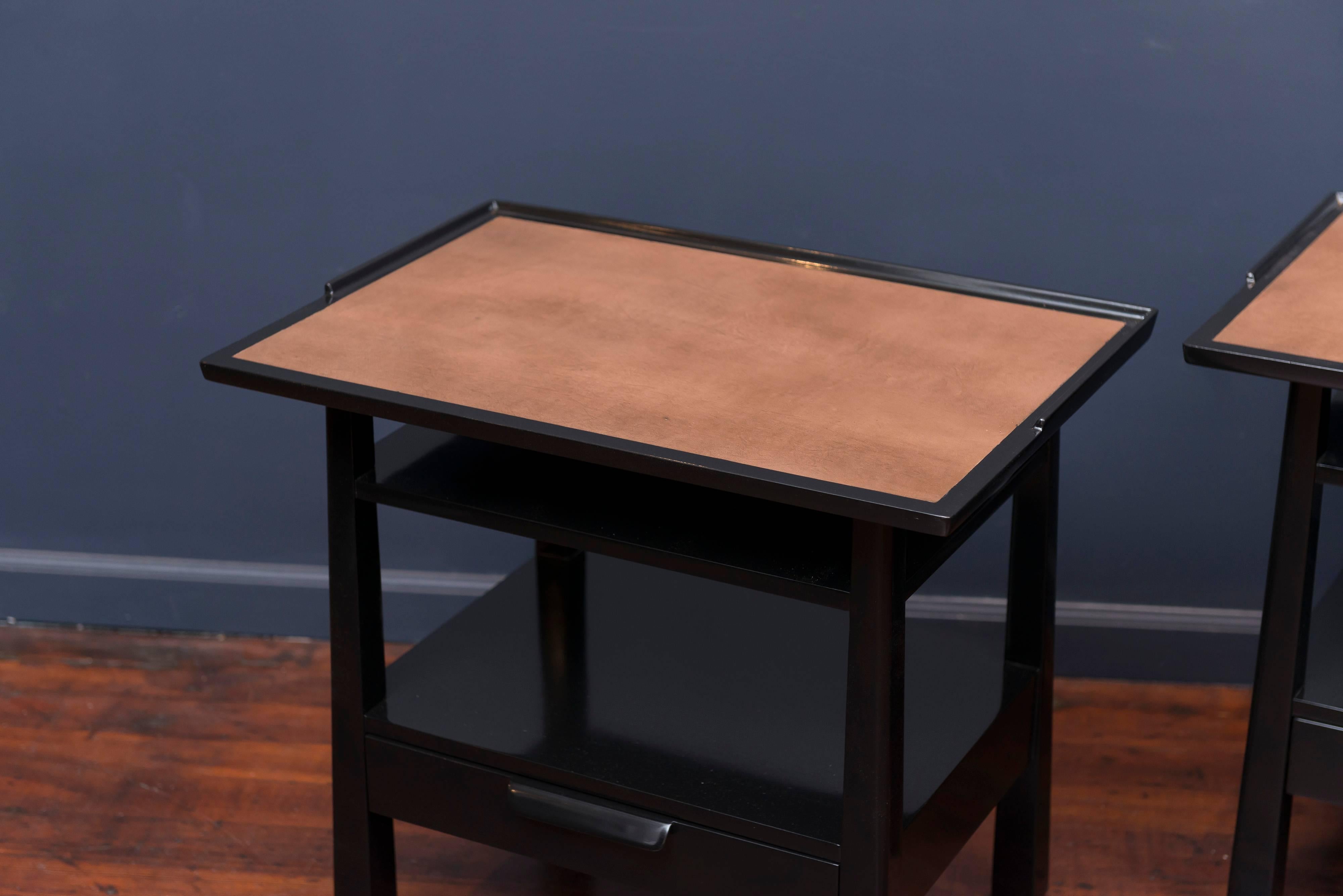Pair of Edward Wormley design side tables made from solid mahogany with leather insert tops. Sculpted single drawer pull with a gallery trimmed top on tapering legs, newly refinished, labeled.