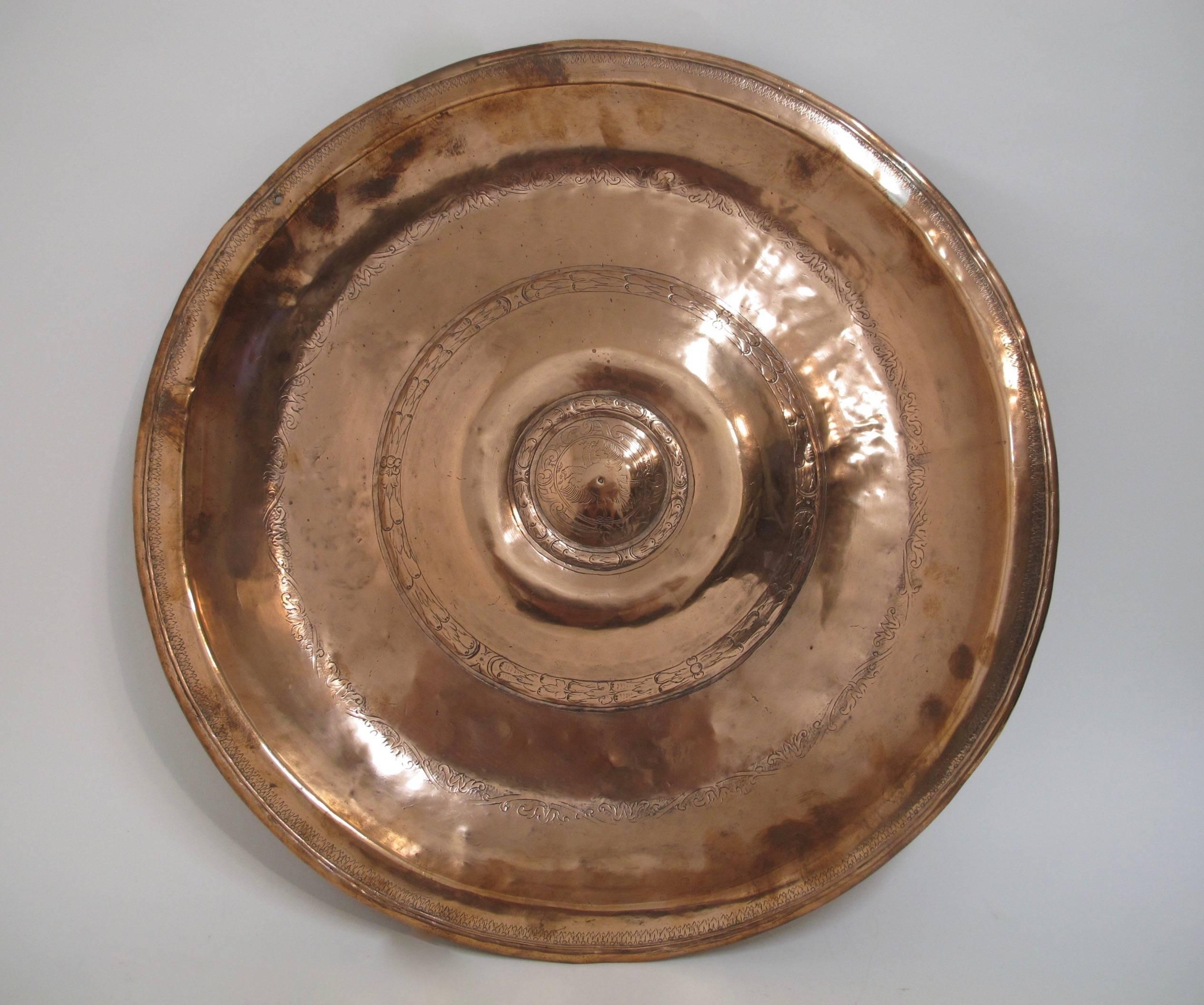 A 17th century or earlier large copper alms dish or alms plate.