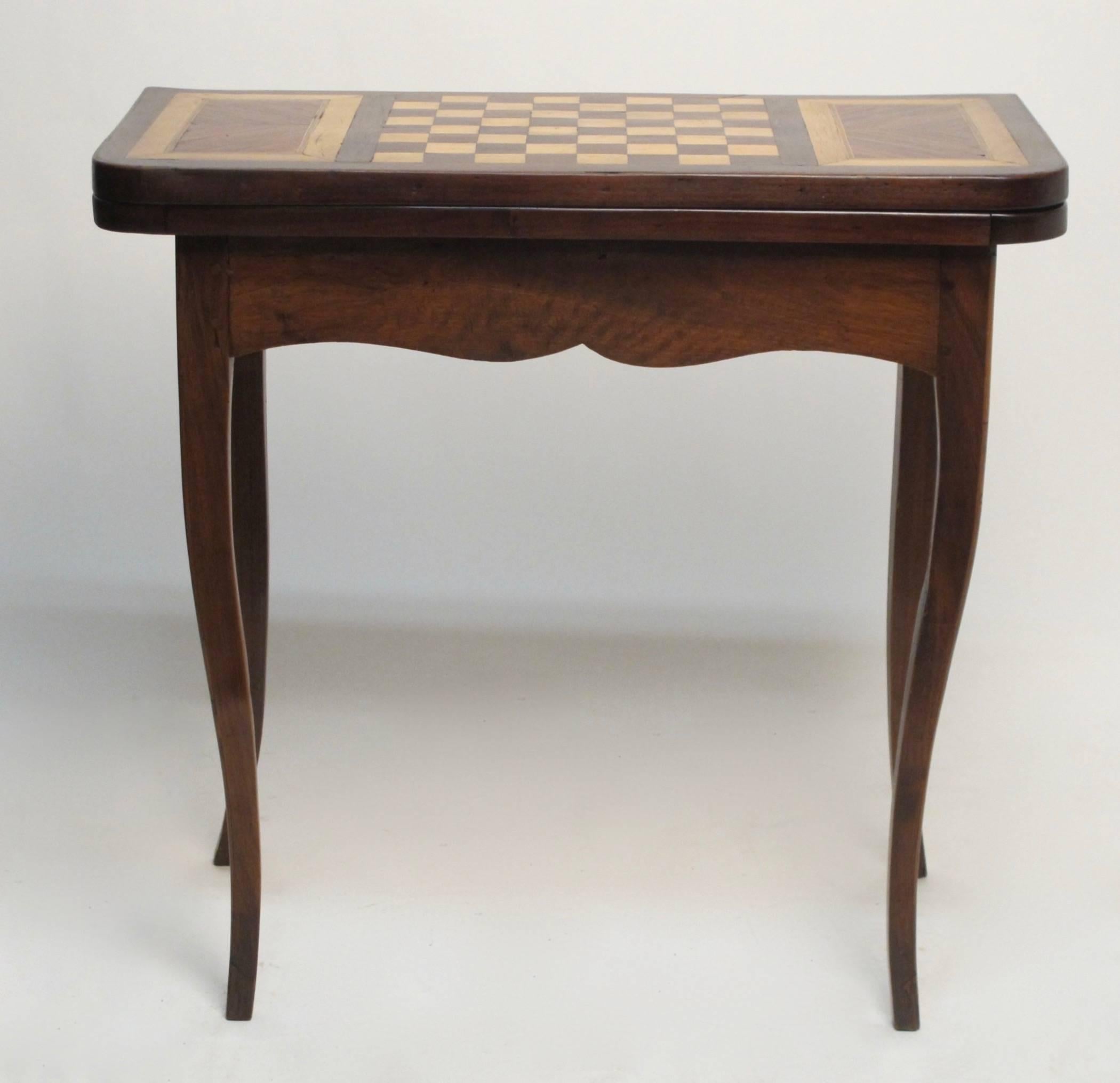 French game table with inlaid chess board, made of mixed fruitwoods with walnut and black walnut. Top flips open to a felt lined surface (felt fabric shows some age and wear). Recently refinished, France, early 19th century.