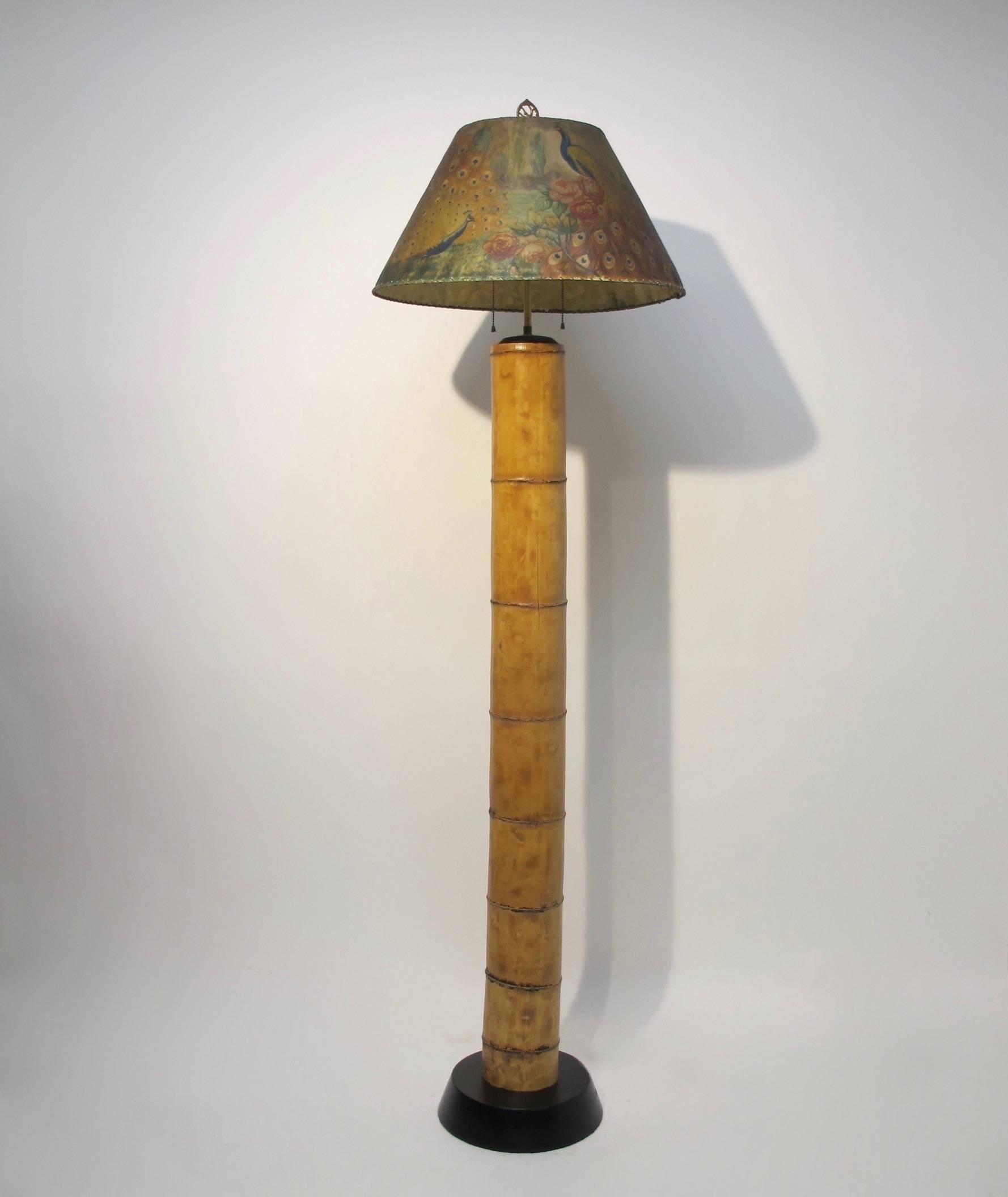 A single thick bamboo shoot mounted as a floor lamp with a beautifully hand-painted shade of peacocks and roses. There is a small old repair to the parchment shade, circa 1920s. Recently re-wired.