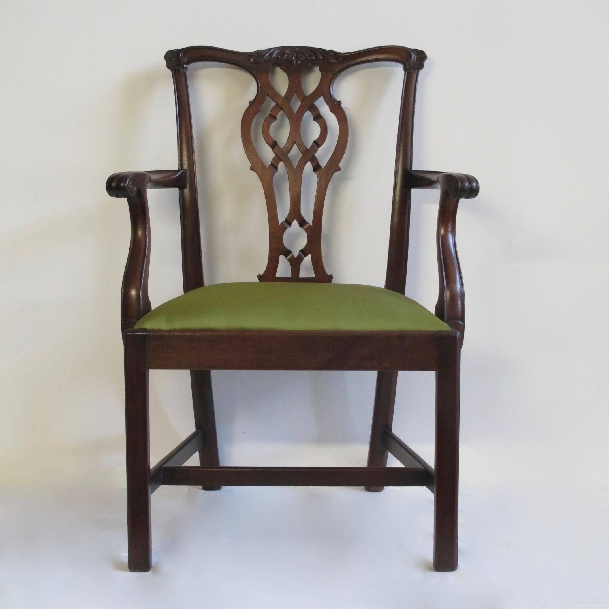 A matched set of 14 Chippendale style dining chairs consisting of two armchairs and 12 side chairs, newly reupholstered. Beautifully hand-carved with ribbon back, acanthus leaf and floret ear detail. Armchairs (handmade) later (early 20th century).