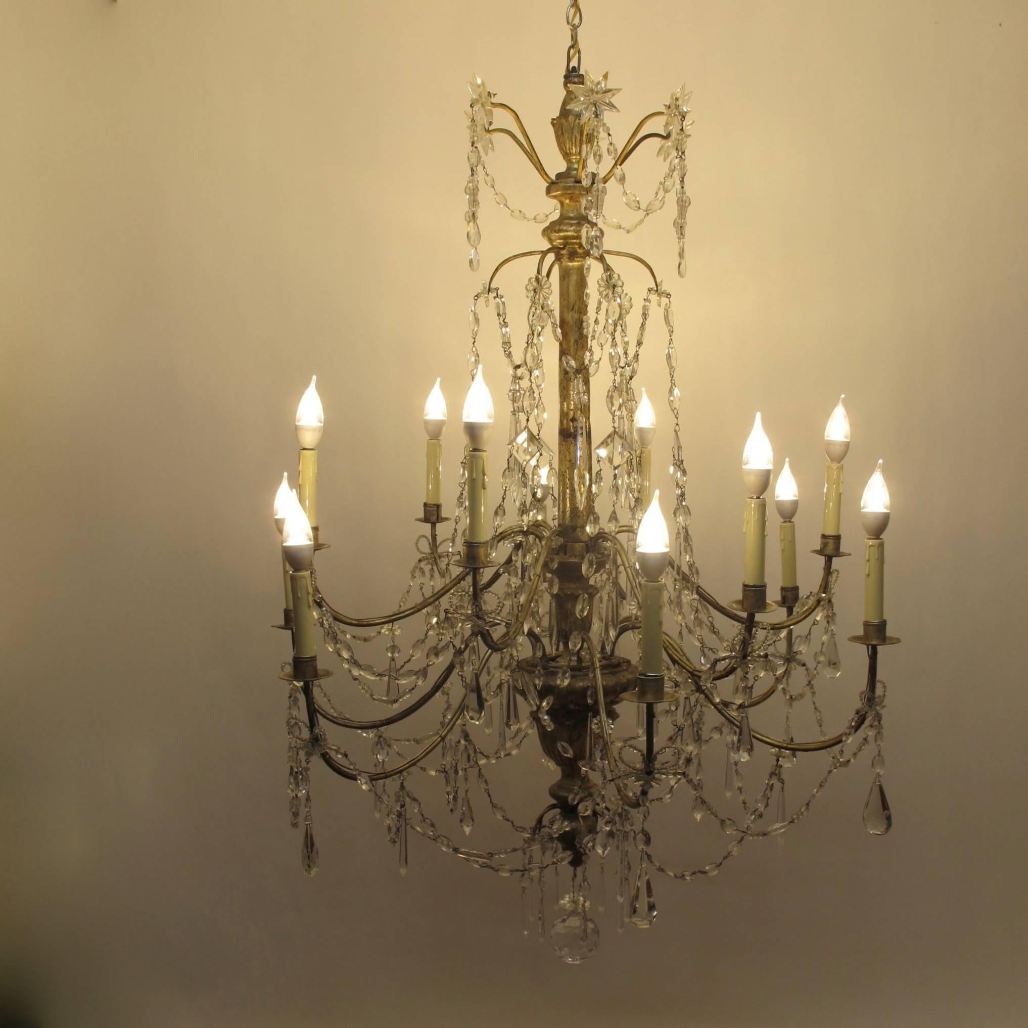 Ein außergewöhnlicher italienischer zwölfarmiger Kerzenleuchter aus dem 18. oder frühen 19. Silbervergoldeter Holz- und Eisenrahmen mit Kristallanhängern und Glasfahnen.
Kürzlich renoviert und elektrifiziert.