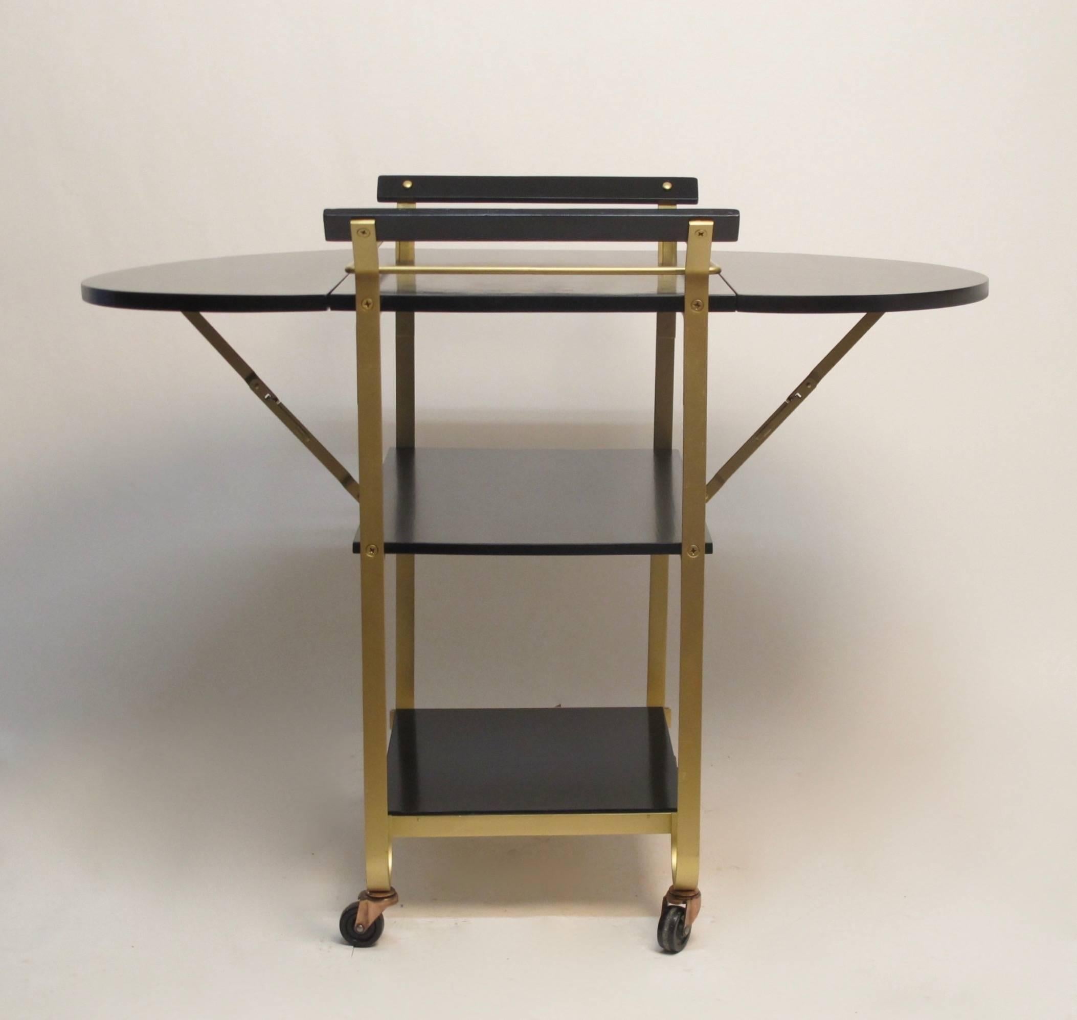 Black lacquered wood and satin brass three-tier bar cart with drop leaves. Each leaf measures 12.25 inches. Completely refurbished and polished. American, mid 20th century.