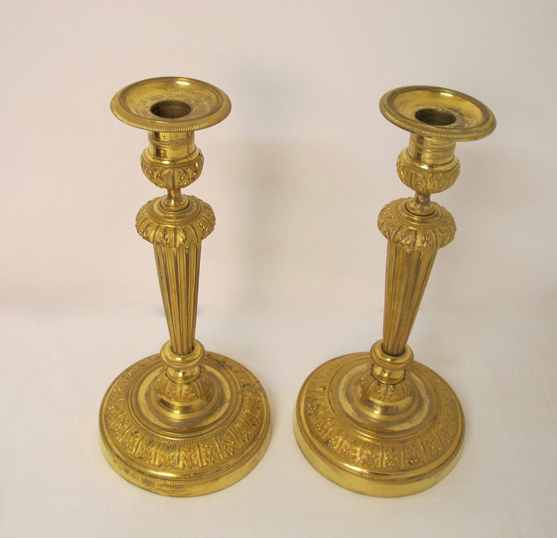 Impressive pair of Louis XVI style gilt bronze candlesticks with bright cut floral design, fluted tapering column. Standing straight and tall with wear of the gilding in areas. To be expected given the age, French, circa 1860.
These have never been
