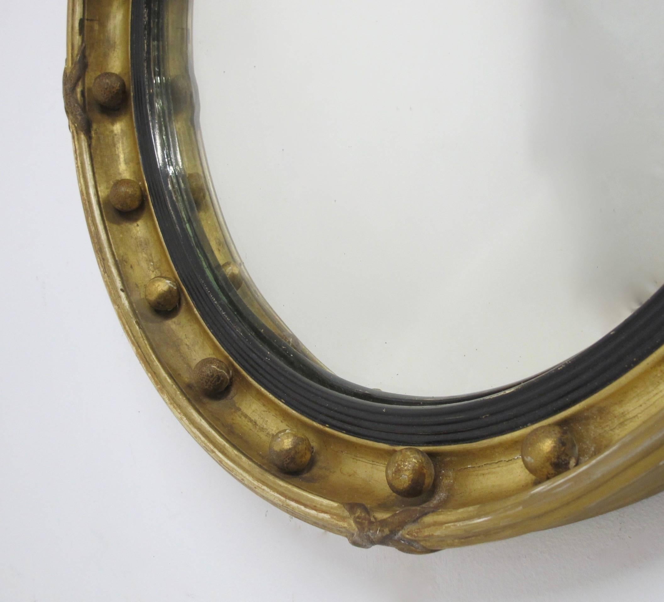 19th century wood frame with ribbed and ebonized inner band, worn gilt finish and original glass. Original mirror shows age spots and a small blemish or flake on the left side.