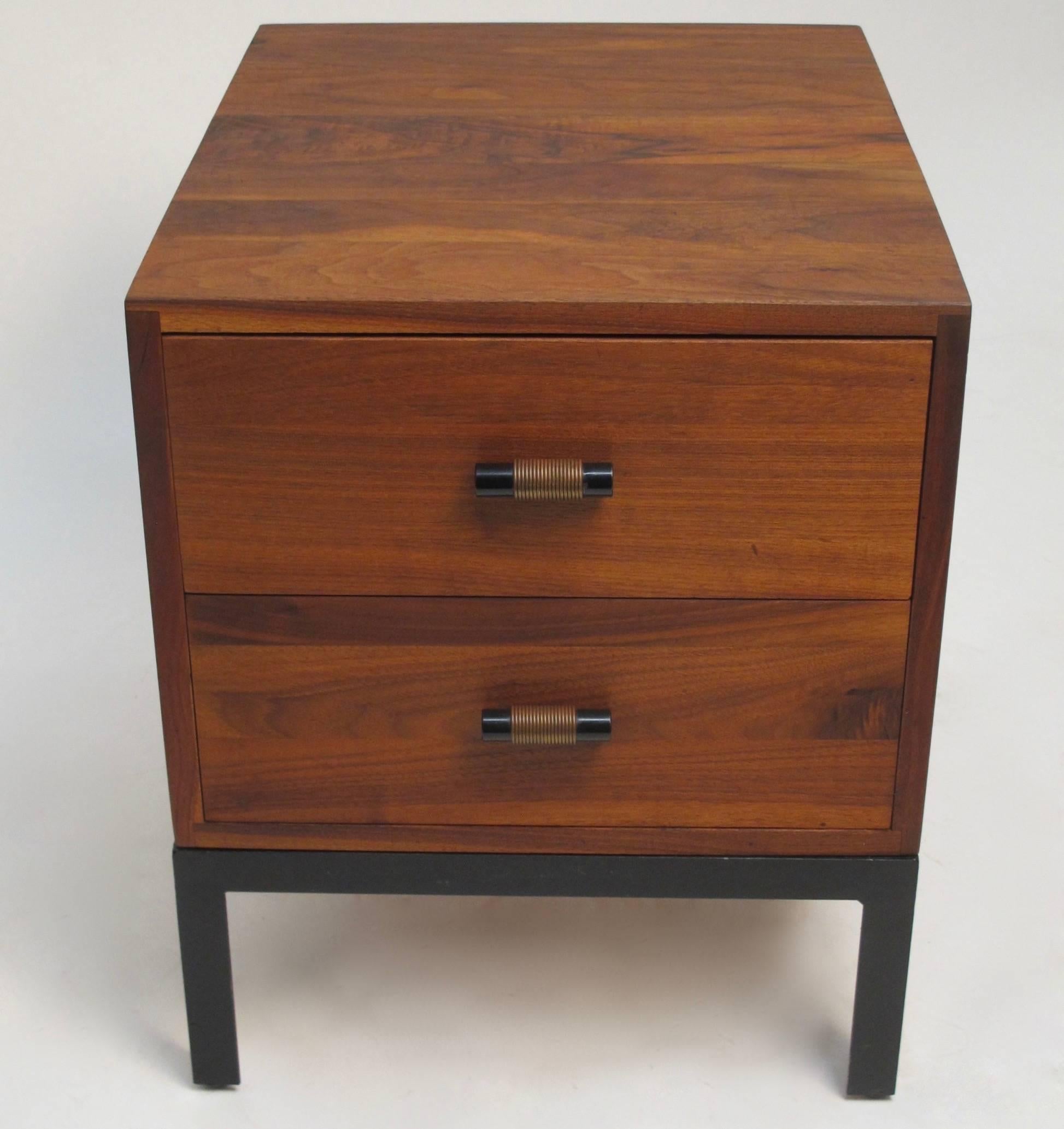 A solid walnut two-drawer chest or side table with wrapped steel pulls sitting on an iron base.  circa 1960s.