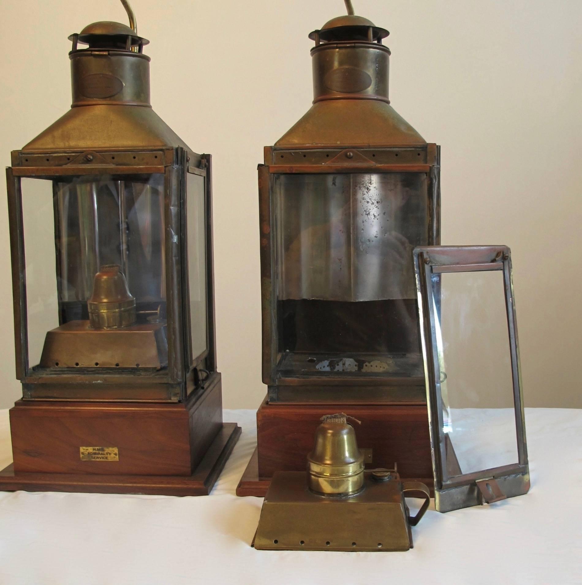 A pair of antique museum mounted ship lanterns intact and completely original from H.M.S. Admiralty Service. Oval plaque on the chimney reads 