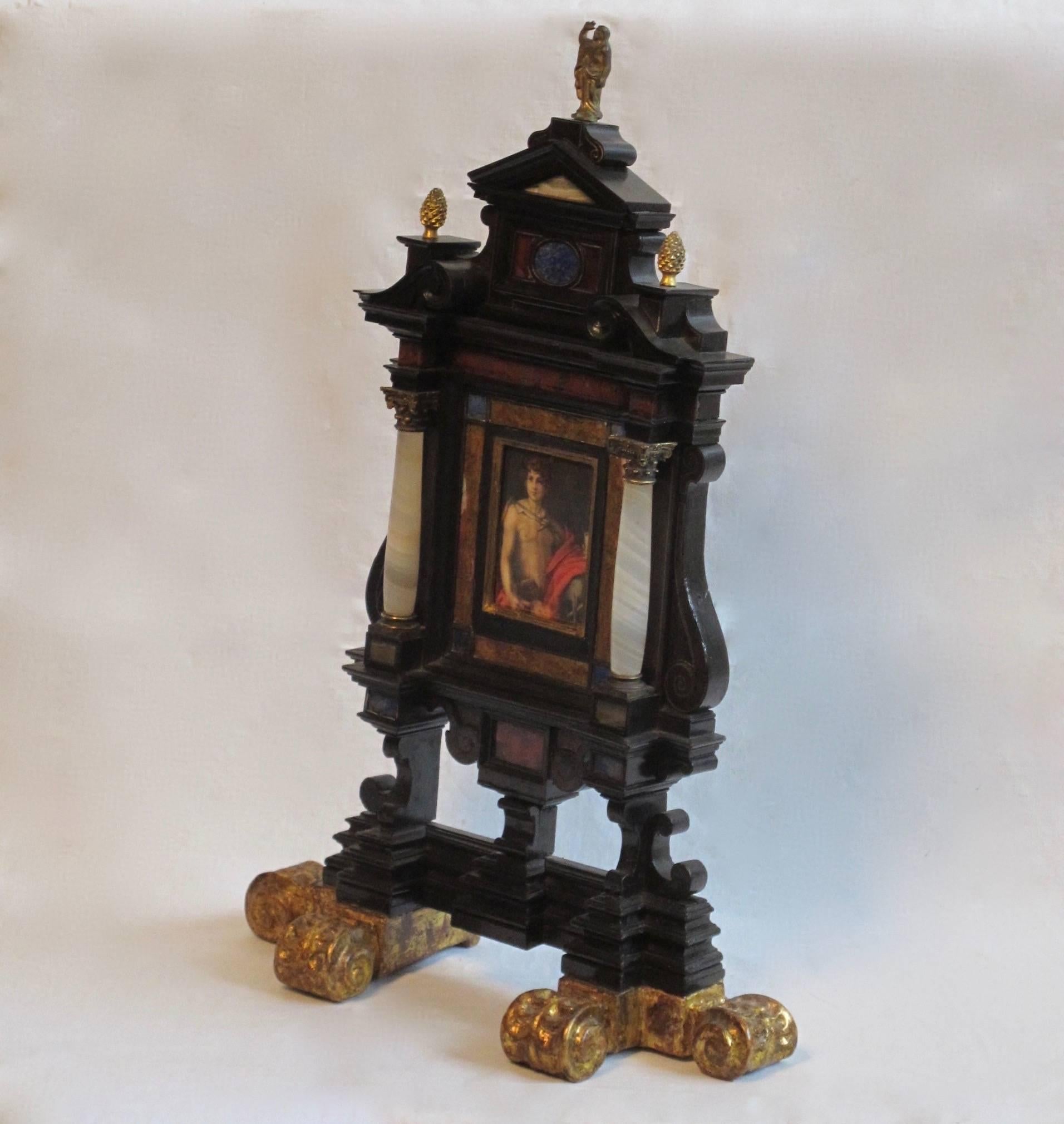 An exquisite Italian Renaissance/Baroque style tabletop / standing ebonized frame with inlaid lapis, carnelian, agate and marble. Having bronze pineapple finials and figure standing atop an arched pediment, the agate columns flanking an early 19th