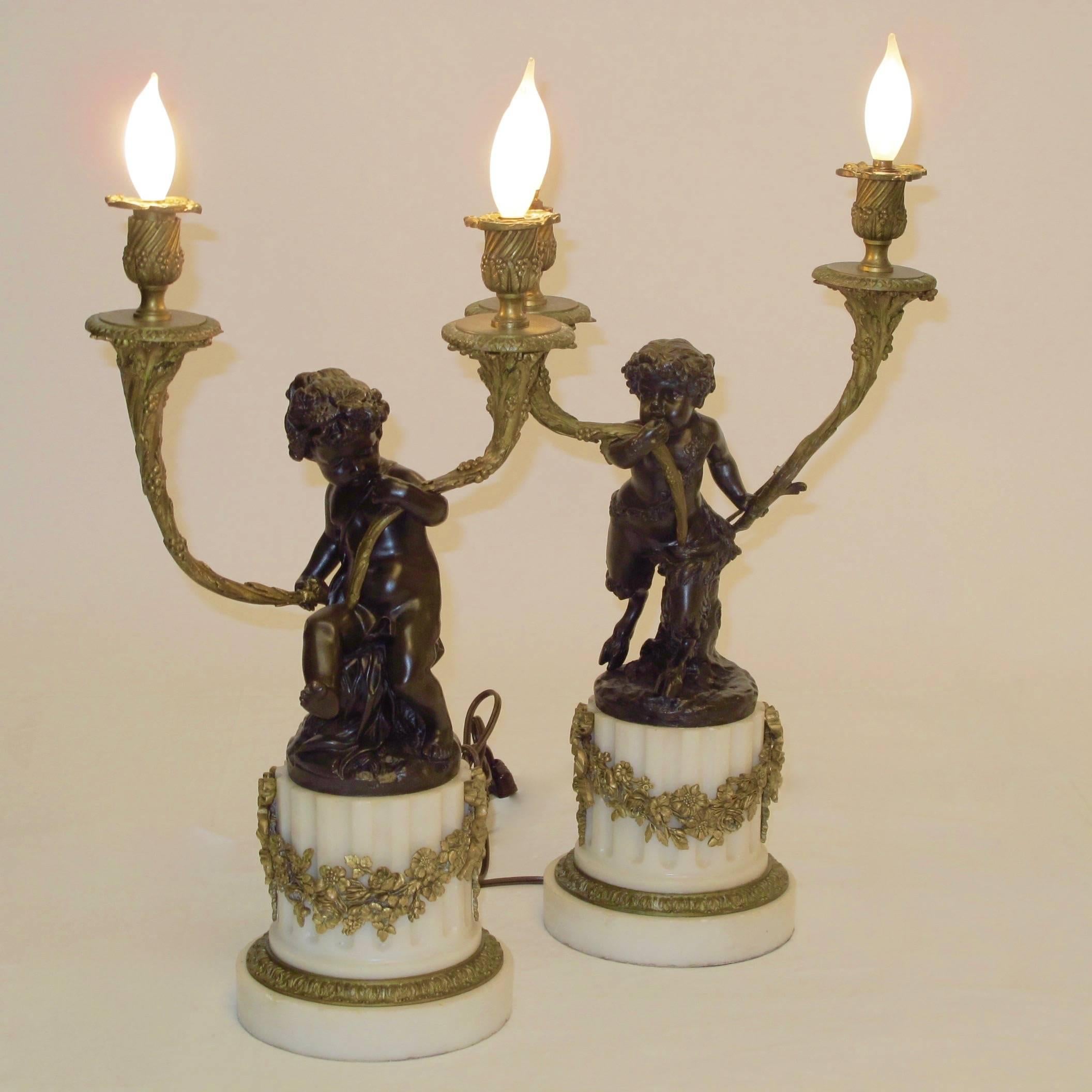 Finely cast bronze figural sculptures on marble bases with gilt bronze decoration. Recently re-wired and hold chandelier size light bulbs.

Claude Michel (December 20, 1738 – March 29, 1814), known as Clodion, was a French sculptor in the Rococo