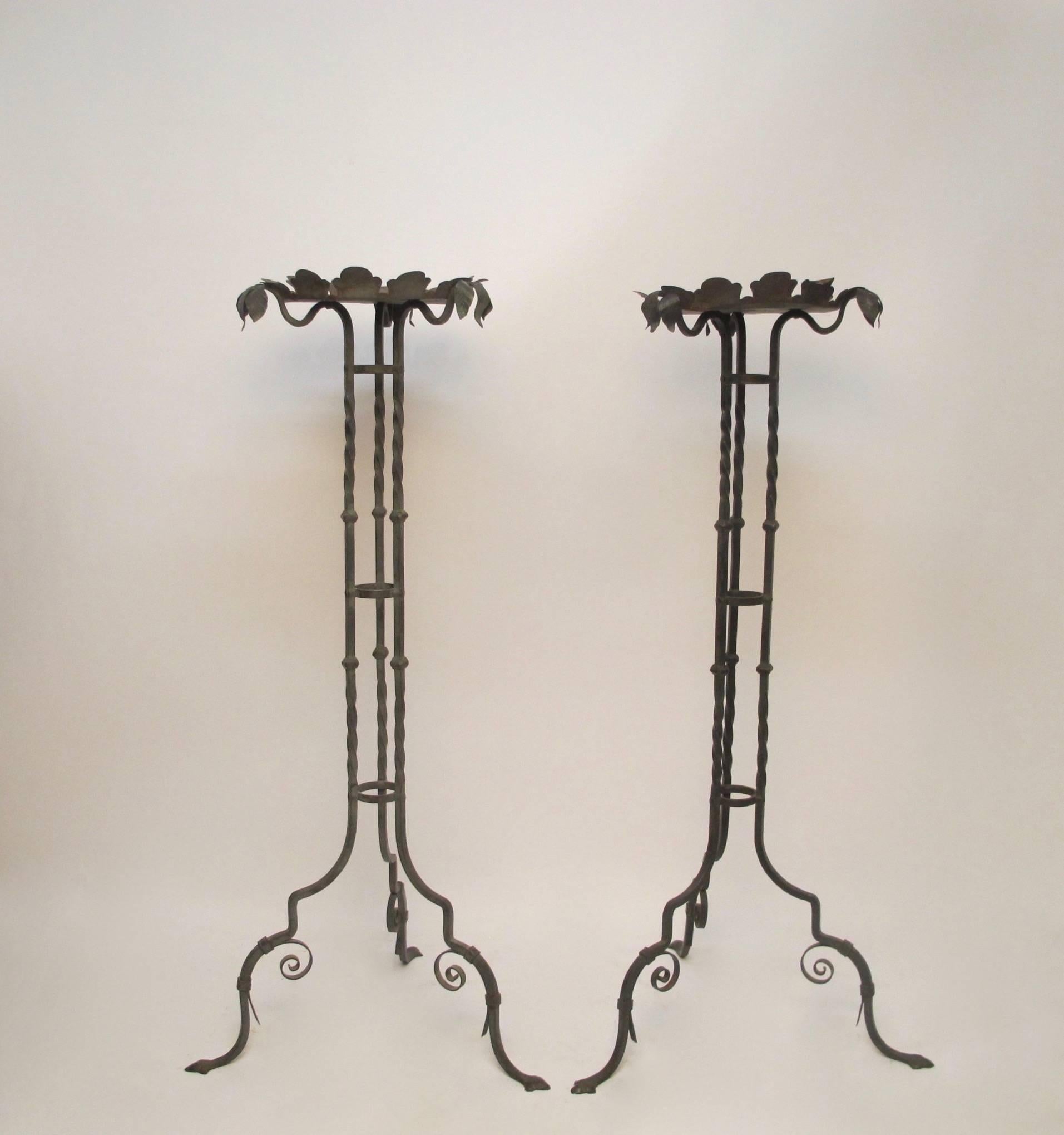 A pair of iron plant stands with verdigris finish. Triple leaf decoration at the end of each support and scallop saucer holder. Early 20th century.