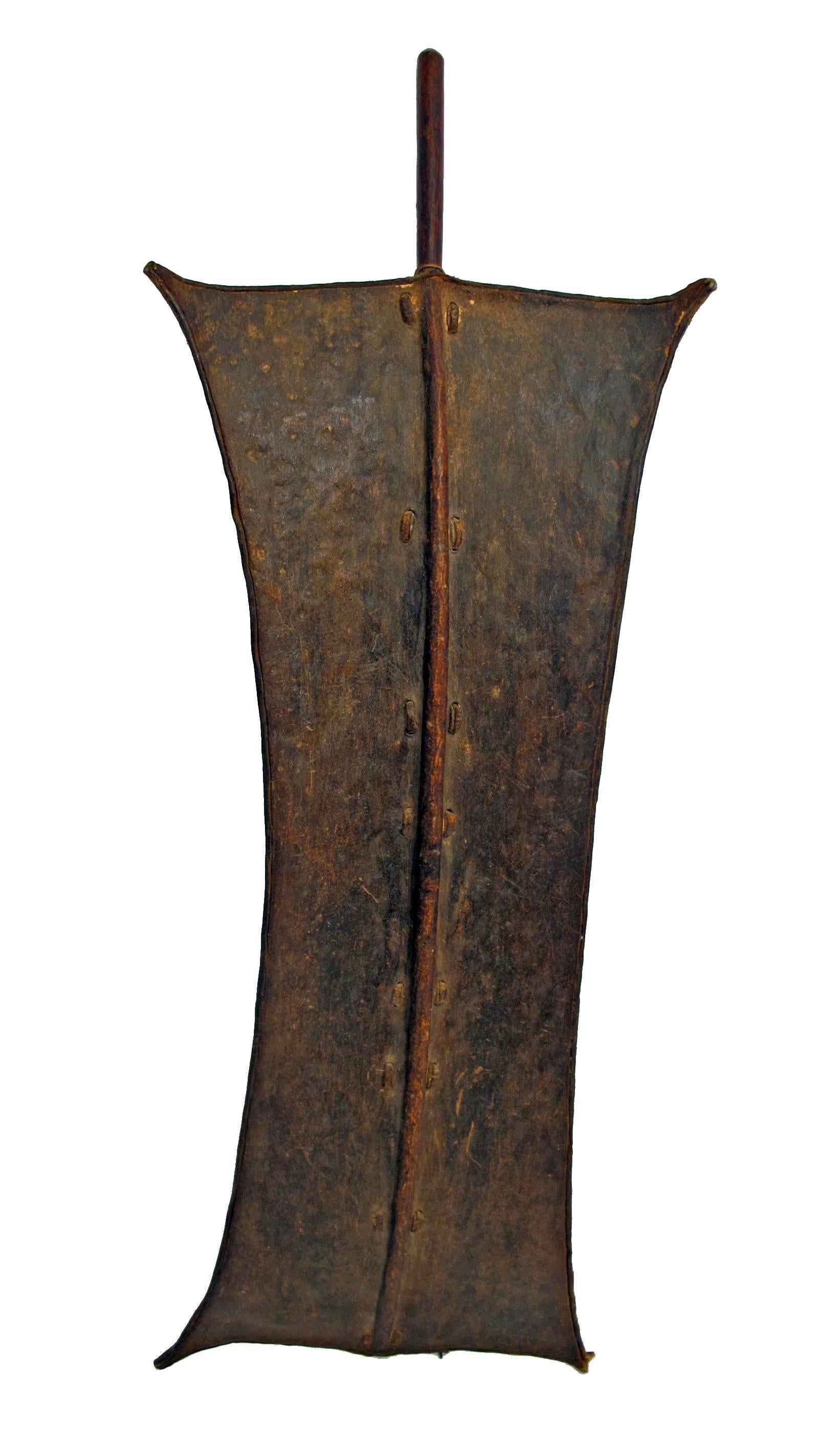 An early 20th century animal hide, wood and leather tops shield from Southern Sudan.