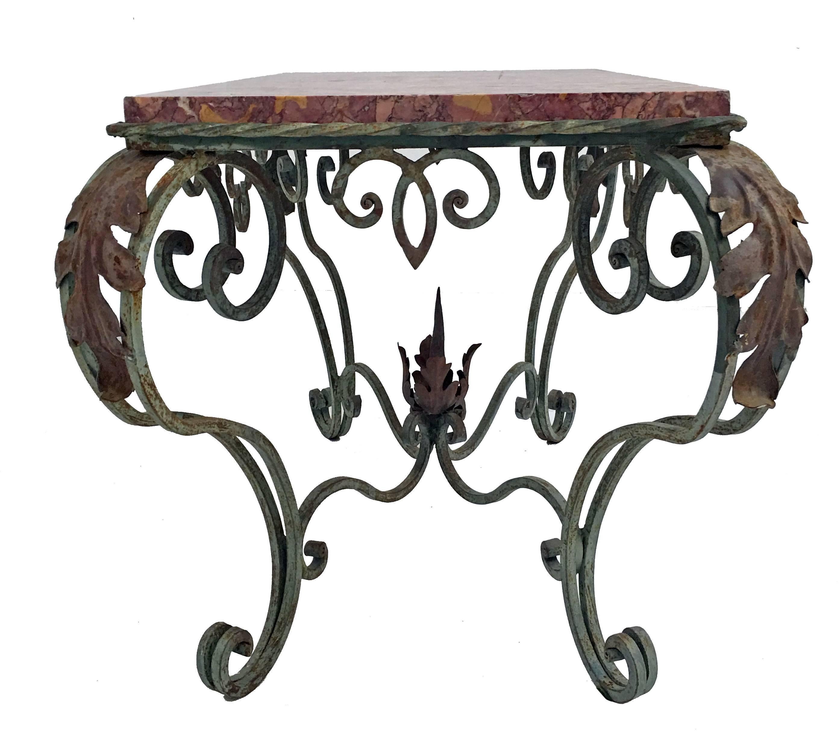 Green painted iron with rusted tole acanthus leaves table and rouge marble top, standing on robust scrolling legs connected to scrolling stretcher with rusted flame finial. Open scroll apron on all four sides, French, circa 1920s.
Could also be